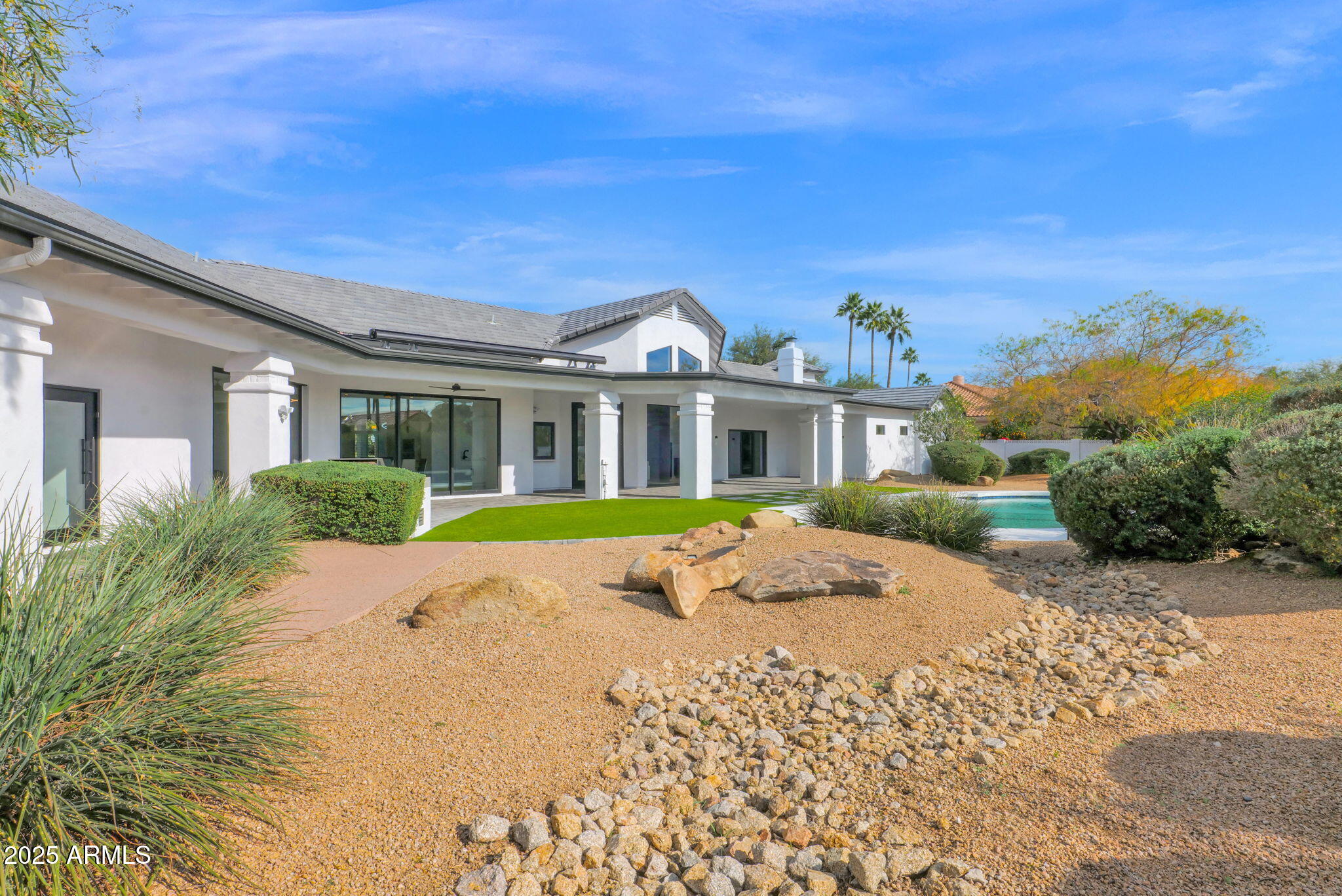 Experience elevated luxury living on nearly an acre with no HOA. This 5,822 sq ft Modern contemporary masterpiece has been reimagined with timeless finishes, warmth, and modern livability. Real wood plank floors, vaulted beam ceilings, and commercial style windows and doors bring natural light and the outdoors in. The chef's kitchen flows into a custom wine wall and butler bar perfect for gatherings and entertaining. The primary suite features a hidden private exercise room, spa-style bath, and massive closets. Step outside to a south facing resort-inspired oasis with an expansive covered patio, sparkling pool & spa, water features, and inviting spaces to dine, lounge, and enjoy beautiful Arizona evenings. Newer roof, newer AC's meaning this is truly a move in ready home.