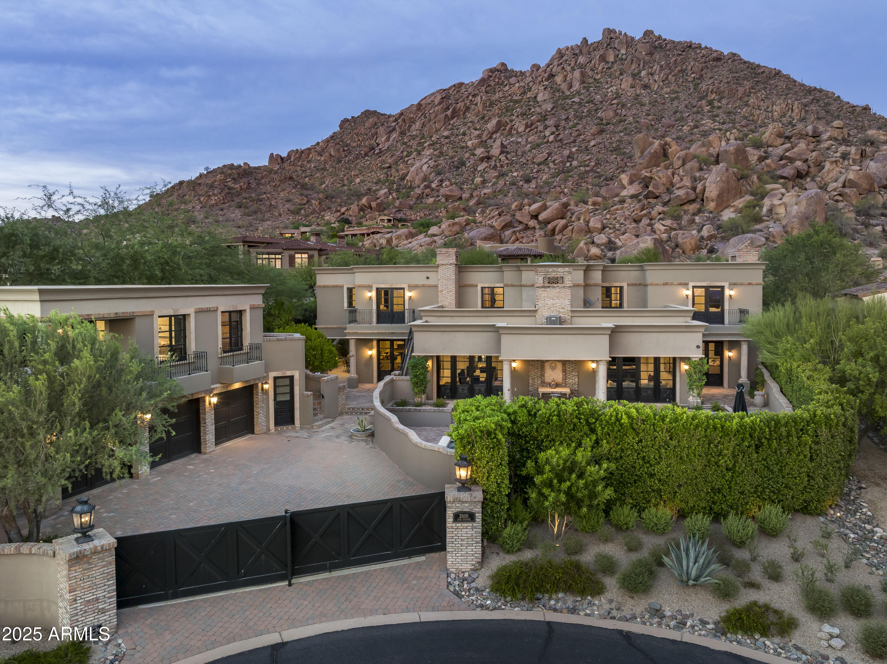 Welcome to 25001 N 107th Place, a breathtaking European-inspired estate gracefully tucked against the iconic boulders of Troon Mountain. Spanning 8,678 sq. ft., including a private guest house and beautiful custom wood doors and shutters throughout the home.  This architectural masterpiece offers 5 bedrooms, 7 baths, including private guest quarters, designed to capture both elegance and livability.

This estate offers a rare luxury—two primary suites, each with its own spa-inspired bathroom. One is located on the main level for ease and convenience, while the second upstairs retreat provides an elevated vantage point with sweeping views, giving owners the choice of two exceptional sanctuaries.

Inside, timeless details abound—cantera stone, custom wooden beams, marble finishes, and expansive indoor-outdoor spaces that embody the essence of Scottsdale living. Multiple fireplaces warm the residence, from the elegant great room to the floor-to-ceiling brick fireplace in the chef's kitchen, which features top-of-the-line appliances and refined finishes.

A private home office ensures space for work or study, and a spacious exercise room to unwind and stay fit, while generous entertaining areas flow seamlessly outdoors.

The backyard is a true resort escape, complete with a sparkling pool and spa with waterfalls, expansive patios, and panoramic city light and mountain views. Every corner of this estate has been crafted for luxury, comfort, and connection with its natural surroundings.
Located within the prestigious gated community of Artesano at Troon Canyon, residents enjoy unmatched privacy, 24/7 security, and close proximity to championship golf, scenic hiking, and all the best of North Scottsdale.

This one-of-a-kind residence is more than a homeit's an experience in timeless luxury and refined desert living.