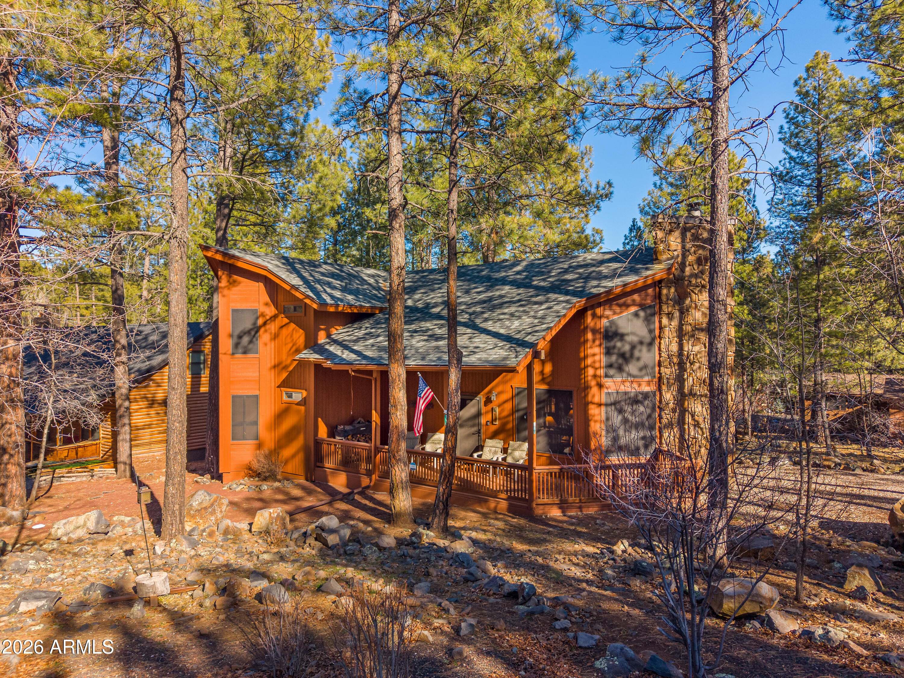 This beautifully maintained Munds Park chalet-style cabin is being offered fully furnished and is ready for you to start enjoying right away. The main level features two spacious bedrooms and two updated bathrooms, providing comfortable accommodations for family and guests. Upstairs, the oversized loft offers flexible space that can serve as a bunk room, game room, home office, or additional sleeping area. Inside, you'll find warm wood flooring, custom built-in bench seating in the great room, and an open, spacious kitchen designed for gathering and entertaining. The stunning floor-to-ceiling stone-faced wood burning fireplace creates a dramatic focal point and adds to the cabin's cozy mountain charm. Front and back decks provide plenty of space to relax, entertain, and enjoy the beautiful mountain setting.