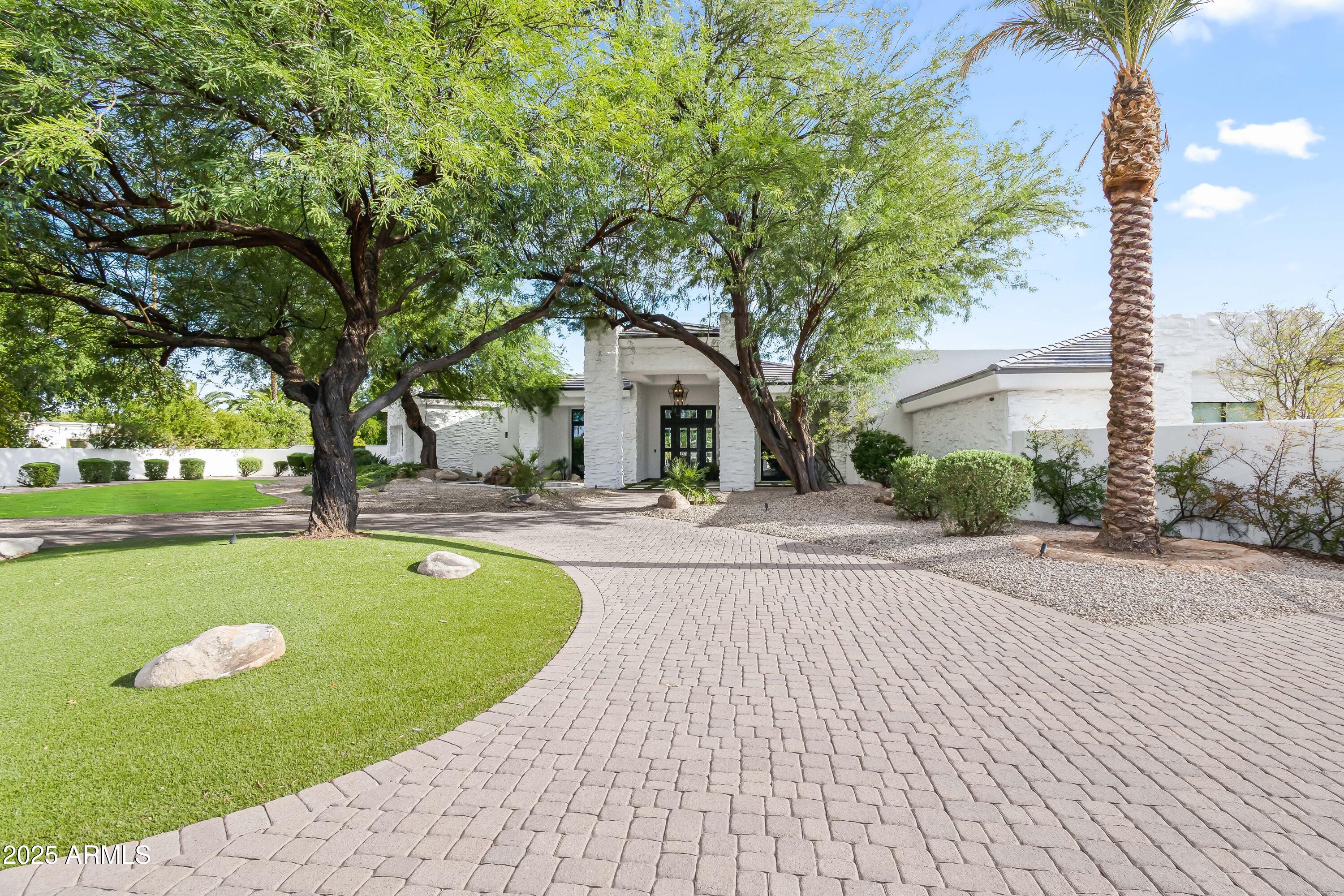An extraordinary estate on one of Paradise Valley's most exclusive three-home streets. Privately sited on 1.19 acres with mountain views, this residence marries timeless architectural elegance with resort-inspired amenities, embodying the pinnacle of Arizona living. Beyond the grand foyer, interiors are bathed in natural light and arranged for both intimate gatherings and large-scale entertaining. Formal and casual dining rooms complement a chef's kitchen appointed with premium appliances, while multiple living areas and a dedicated office offer both sophistication and practicality. The walk-out lower level extends the experience with a private theatre, game room, and versatile recreation spaces designed for leisure and entertainment. A thoughtful split-bedroom plan ensures privacy, with each en suite crafted to the highest standard of comfort and finish. The grounds are equally impressive: a heated pool and spa, sport court, putting green, outdoor kitchen, and expansive patios, all framed by manicured landscaping and a dramatic mountain backdrop. A gated motor court and four-car garage with generous storage provide both convenience and security. Ideally positioned near world-class resorts, fine dining, luxury shopping, and premier golf, this estate offers an unparalleled blend of exclusivity, privacy, and resort-style living in the heart of Paradise Valley.
