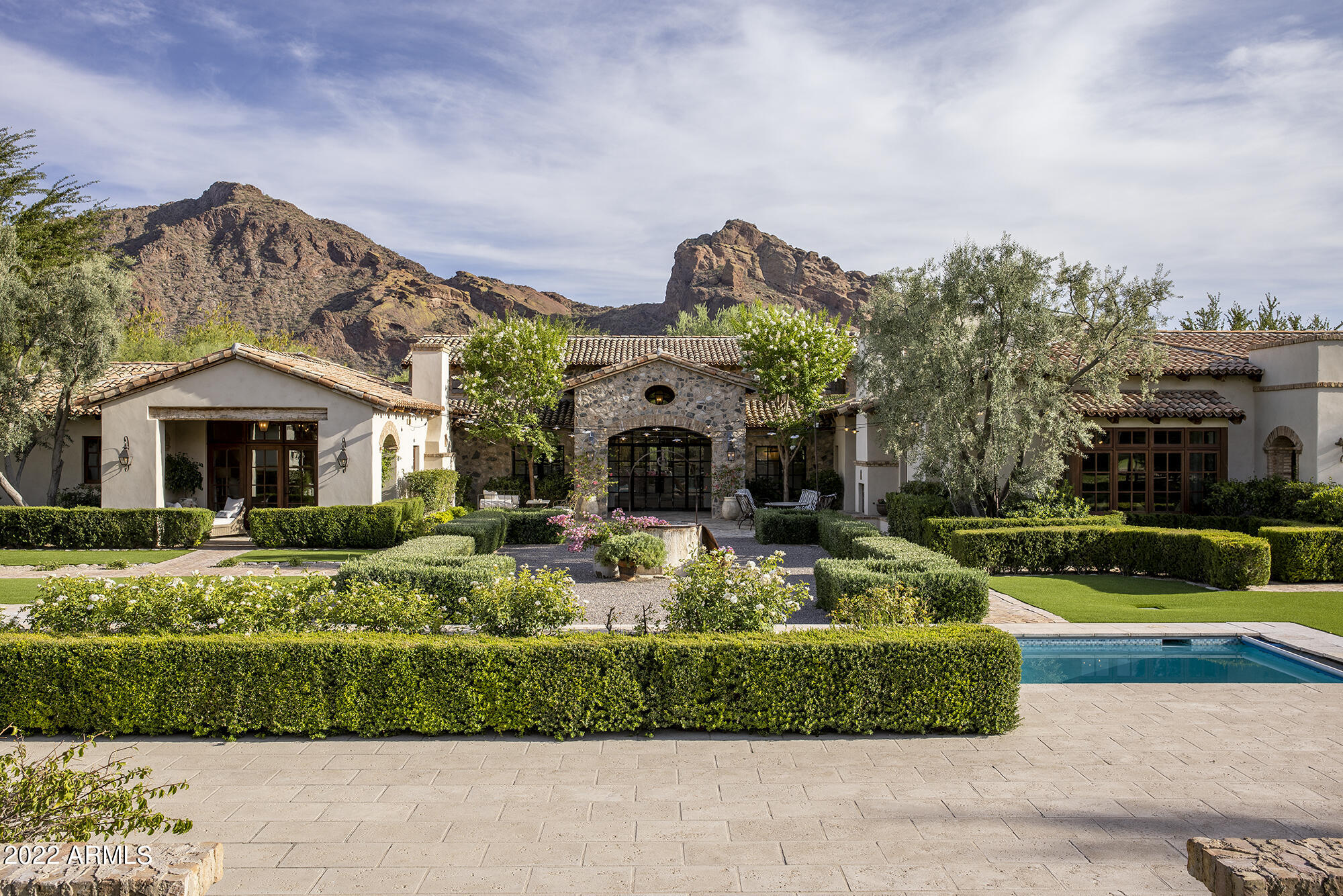 This quintessential European French style farmhouse is relaxed yet sophisticated, offering a level of exceptional detail and quality located in the heart of Paradise Valley.  Built by Calvis Wyant in 2009 with refined taste and quality construction, the 2.14-acre homesite is situated on the Paradise Valley Country Club golf course, capturing unobstructed views of Mummy Mountain.  With an ambiance of old world country estate, a private gated drive invites you to this one-of-a-kind masterpiece of timeless appeal.  Offering an elegant section of antique building materials and finishes from throughout Europe, this home unfurls before you as you cross the threshold of the 19th century antique French oak front door with not one detail overlooked to create the authenticity of an European estate home including plaster walls, 1" solid wide plank French oak flooring, reclaimed French oak timber beams and trusses, Hope's solid steel handcrafted windows and doors, French and Italian antique light fixtures and iron work throughout the home. 
At the heart of this home is an amazing kitchen with custom European style quarter sawn white oak cabinetry, Belgian bluestone countertops, French antique parefeuille terracotta tile flooring, and an antique reclaimed brick fireplace opening to a beautiful great room. In the expansive great room is an 18th century antique French limestone fireplace surround and a wall of Architectural Traditions incense cedar wood custom dual pane doors, opening to a large covered reclaimed antique Spanish brick patio consisting of an outdoor bar/kitchen and large dining area. Room after room opens to expansive covered patios, courtyards and walkways with multiple outdoor fireplaces and cozy seating areas to take advantage of the beautiful setting and the perfect Arizona climate. The estate boasts six fireplaces, a four-car garage, wine cellar, 1200+ square foot private entry guesthouse, European style pool and cabana, roof deck with unobstructed views of both Camelback and Mummy Mountain, and a sliding gate which opens the backyard to the Paradise Valley Country Club golf course. This lovely 11,412 square foot residence is a beautiful and warm family home as well as a tasteful, elegant estate in which no detail has been overlooked.