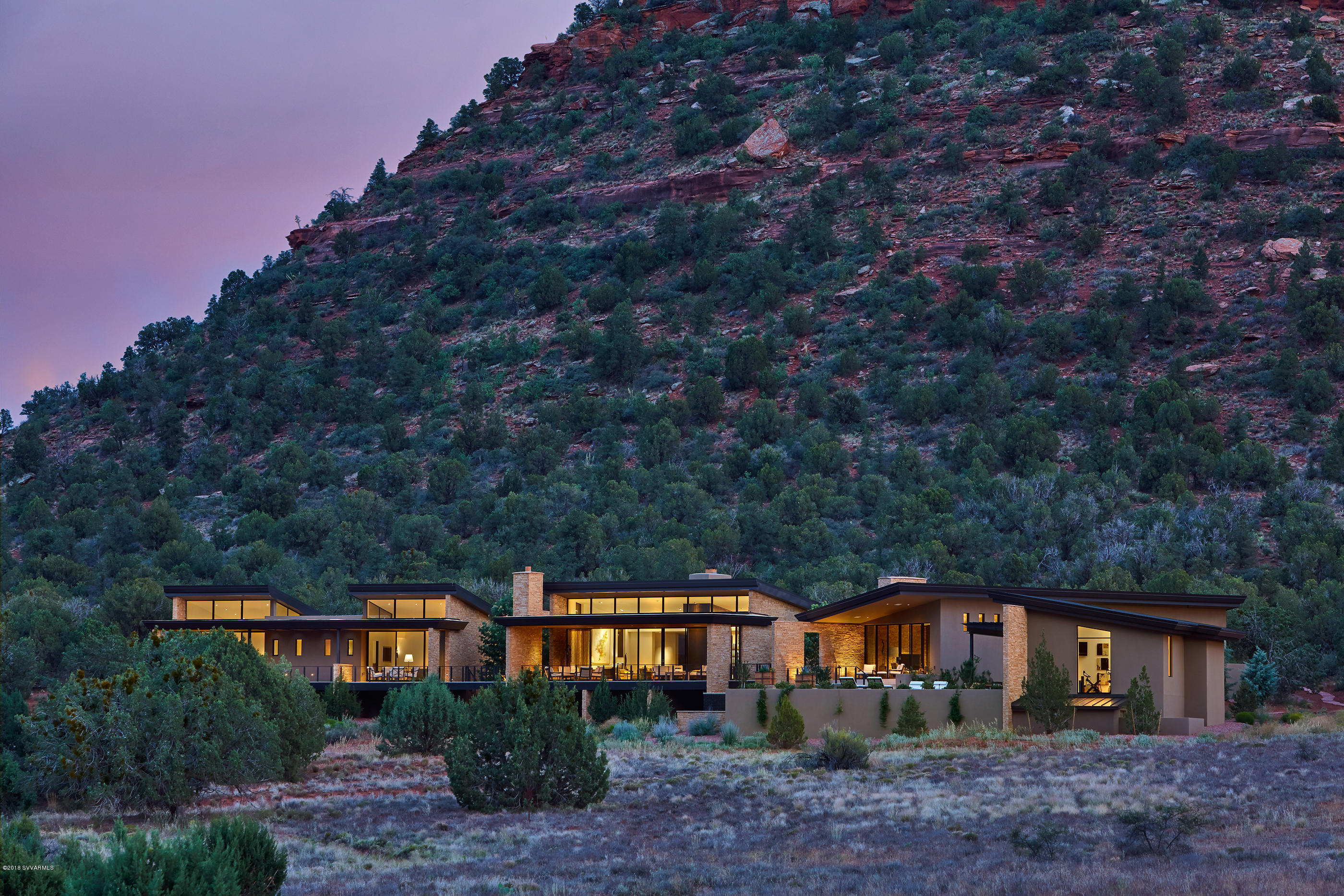 This stunning desert contemporary home sits harmoniously on its 4.65-acre site backing to pristine National Forest land, capturing the incomparable red rock vistas and mountain views within the beautiful and prestigious Aerie community in west Sedona. Combining stunning architecture, a fully single-level floorplan that flows seamlessly from end to end, heightened attention to every exquisite detail,and majestic panoramic views, this is a true world-class residence on a level all its own in Sedona.The long, gated private driveway brings you up to the elegant entry with beautiful desert landscaping. A soulful sense of privacy against the National Forest blends into the expressively inclusive nature of the home and its welcoming spirit as you approach the front entry. (see more) As the custom entry door swings open, you're greeted by the dazzling and expansive views from an opposite wall of glass. The intimate and the graceful flow that envelopes you as you stand in the naturally lit entry foyer is an overwhelming experience. The home is made up of pavilions that float over the natural washes of the property. The main pavilion is made up of the Great Room, Kitchen, Office, and Den/Media Room. You will first move seamlessly into the open Great Room, drawn by the wall of windows out to the breathtaking views. This main living space is anchored by a floor-to-ceiling custom fireplace, which is clad in natural wood and steel and lined with polished stainless steel. This stunning feature provides the sophisticated architectural separation between the airy Living and formal Dining areas. Across the broad skylight gallery hallway is the very spacious Gourmet Kitchen, detailed on a level for the most discerning chef, and includes a grand island with white, cream and back granite that has under lighting, which gives it an even more dramatic affect. This kitchen includes a large gracious breakfast area and a butler's pantry. A wall of windows opens to a private courtyard with its outdoor kitchen, water feature, and dining area, and situated to still capture the striking unmatched red rock views. This main pavilion also houses a private Office and a separate Den/Media room for enjoying a quiet evening watching your favorite movies. 

The second pavilion is accessed through the gallery hallway and across a large glass-enclosed bridge and is the Master retreat. The gorgeous Master Bedroom, complete with a fireplace and generous sitting area, has unbelievable views that allows one to relax at the end of a long day enjoying the many hiking and biking trails around the property. The Master Bath and closet have everything one could imagine, with a steam shower and soaking tub, and a gloriously spacious his and her custom closet. The master bath is finished with exquisite tile and glass throughout and inset with gold leaf. The purity of this Master retreat is completed by the seamless access off its private patio to the negative edge pool, a breathtaking setting that brings butterflies to your heart.

There is a luxury Exercise Studio on this side of the home that includes an indoor steam shower and lovely outdoor shower. It is situated off the pool and makes up the third pavilion. This area is certainly suitable for transforming into a full Guest House. It also captures the full red rock view experience in sweeping fashion, stretching all the way into west Sedona and beyond.

Across the home on the other end in the fourth pavilion are two spectacular Guest Suites with generous sitting areas, en-suite gorgeous luxury bathrooms, and private patios to take advantage of the magnificent views. Your family and friends will be treated to a level of relaxation and privacy as part of this retreat-like setting, while experiencing the forever changing play of light and shadows on Sedona's world-renown red rocks.  

An extensive outdoor view patio connects all sections of the home, providing an invitation to experience this world-class setting. There is a warmth and pronounced cheerfulness embodied in this home, captured in the refined and stunning finishes that are further elevated by the generous use of natural light and beautifully proportioned spaces. You will never want to leave

With state-of-the-art features throughout, attention to even the most intricate details, world-class architecture in a world-class setting, this thoughtfully designed desert contemporary home leaves nothing to be desired. It is carefully placed on the site as if it grew out of the terrain. The stone covered fin walls that delineate each area and bisect the home are from stone quarried not far from the site so that they blend with the red rocks of the surrounding area. The glass bridges and day-lit gallery hallway that runs the entire length of the home create a connected, flawless experience and allows for natural light and unparalleled views from every major room. If you're drawn to the very best in a true world-class home, you will fall in love at first site with this personal luxury residence.

Sustainable Design Intent and Innovation:

This luxury residence is designed to be as low impact on the site as possible and to also use minimal mechanical ventilation. The pavilions allow for each section of the house, while not in use, to be essentially shut down. There are 7 heating and cooling zones and there are 4 separate water heaters. The home is a smart home that is state-of-the-art. Most rooms have black out screens or sunshades. Natural day lighting strategies were used in each room to minimize the need for lighting during the day. The rooms on the north side of the home have large clerestory windows above a light shelf that helps to bounce light deep into the rooms, while the light shelves become covered patios that allow for covered outdoor living during the rainy season. The art gallery which runs the entire length of the house and ties the pavilions together is lit during the day with carefully designed skylights that are long linear slits in the ceiling with diffusers that allow light to enter the core of the home all day without allowing direct light to hit the art collection on the walls. Glass garage doors allow the garage to be naturally lit during the day as well. All rooms were designed to have operable walls of glass that open to the covered patios that allow for natural ventilation and extensive indoor/outdoor living. A 94 panel 23.5 kw solar system is seamlessly integrated and hidden in the design to supplement the energy use. 
See Documents for a list of special features.