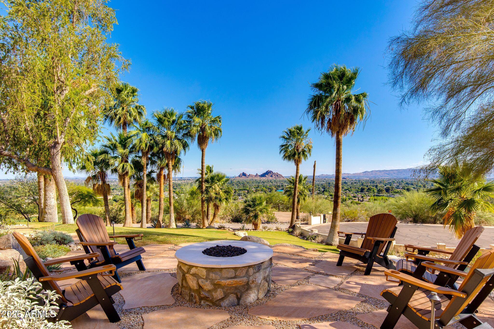 Perched above the Phoenician Golf Course, this mountainside home provides one of the best view lots in all of Phoenix. Located at the end of a quiet cul-de-sac on nearly an acre, this exceptional 5 bed, home offers 3,987 SqFt of thoughtfully designed living space with a desirable split floorplan.
The primary suite and dedicated office are privately positioned away from the secondary bedroom wing, creating an ideal layout for both everyday living and guests. Two spacious living areas with gas fireplaces, along with a dedicated dining space, provide multiple settings for entertaining, gathering, or relaxing.
The beautifully remodeled kitchen blends modern functionality with timeless character, featuring custom cabinetry, stainless steel appliances, and a striking brick accent wall. It opens seamlessly to a wrap-around deck where sweeping mountain and valley views set the stage for morning coffee, sunset dinners, and effortless entertaining.
Outdoor spaces continue to impress with two inviting sitting areas anchored by gas firepits, all framed by the surrounding desert landscape. A versatile bonus workout room or flexible space, conveniently located off the two-car garage, adds further adaptability to the home.