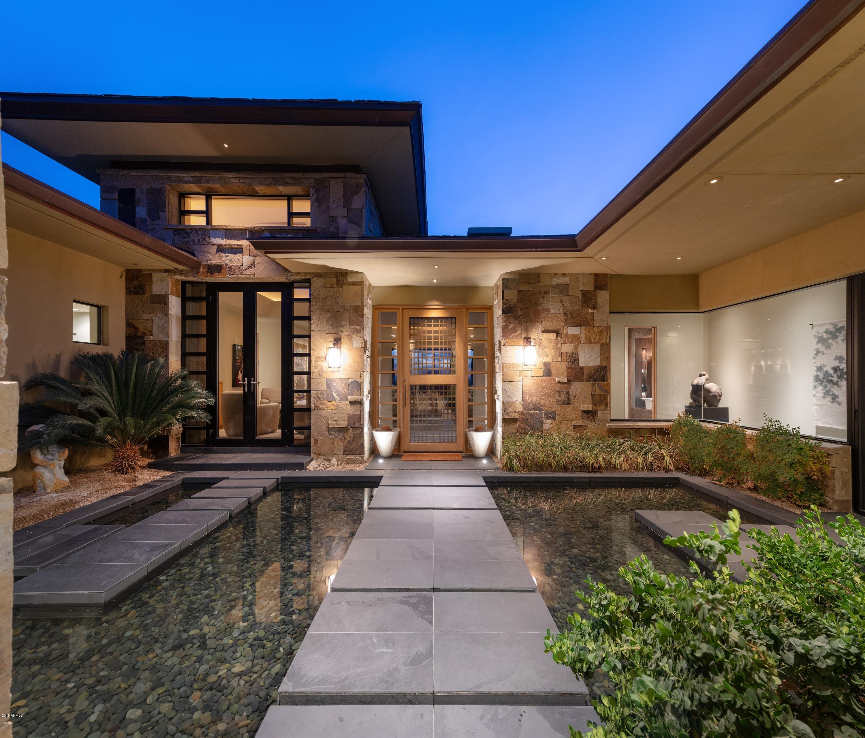 Serenity, Livability, Functionality and Elegance describe this Asian Contemporary in the Desert residence.  The exterior architecture from the pagoda like multiple rooflines with generous overhangs and the dry stack mosaic sandstone facade to the gracious entry walkways over water create the feeling of mental coolness and comfort.  Inside, the spacious great room floor plan seamlessly combines seating, dining, wet bar and large kitchen for small intimate gatherings as well as large entertaining affairs.  With the glass wall systems open the dividing line between inside and out magically disappears allowing the desert drama to unfold with the magnificent western panoramic views.  The attention to detail in the home; plank wood ceiling vaults, slab-frameless cabinetry, dry stack mosaic sandstone floor to ceiling fireplaces, floating shelving and cabinetry, slate, porcelain and hand scraped stained bamboo floors, concrete and granite counters makes it the perfect balance of form and function.  High-end appliances; Miele, SubZero, Sharp, Dacor, Asko, Whirlpool, Nutone and Scotsman provide efficiency and convenience.  The 4 ensuite bedrooms and separate office allow privacy at the same time being integrated with the rest of the home's natural flow.