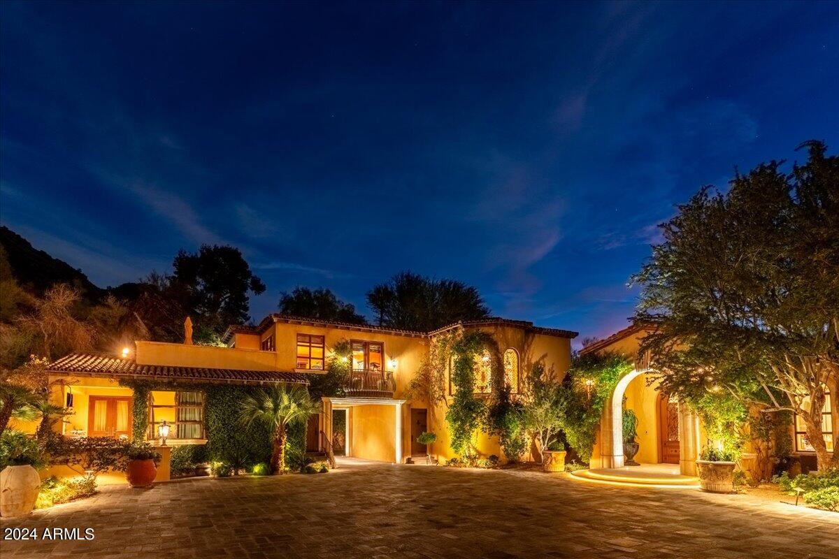 An authentic Italian villa-style home in Paradise Valley stands as a masterpiece of architecture and design.  This majestic property, nestled in the heart of the Sonoran Desert, harmoniously blends classic Italian elegance with the distinctive desert landscape.  The home's exterior, characterized by rustic stone facades and terracotta roof tiles, evokes the timeless charm of Tuscany.  Verdant gardens with native plants, cypress trees and cascading bougainvillea surround the home, creating a serene oasis. As one enters through the private wrought-iron gates, a beautiful stone driveway leads to the grand motor court arrival experience. The foyer opens to an expansive living space with high, coffered and beamed ceilings. Oversized custom windows and doors leading to multiple covered patio and balcony spaces ensure great natural light and seamless indoor to outdoor living throughout this residence. The heart of the home is the gourmet kitchen, equipped with very high-end appliances, custom cabinetry and a large island, perfect for entertaining.  An adjoining family room with grand fireplace offers a cozy retreat.  The residence boasts multiple bedrooms, each with en-suite bathrooms featuring highly detailed fixtures and finishes, recalling the luxury of Italian design. The property includes a serene infinity pool, blending seamlessly with the horizon, and a plethora of gardens and mature trees, providing both privacy and a connection to nature. This amazing residence is more than just a home;; it's a piece of art, offering an unparalleled blend of luxury, comfort and the beauty of the Arizona landscape.