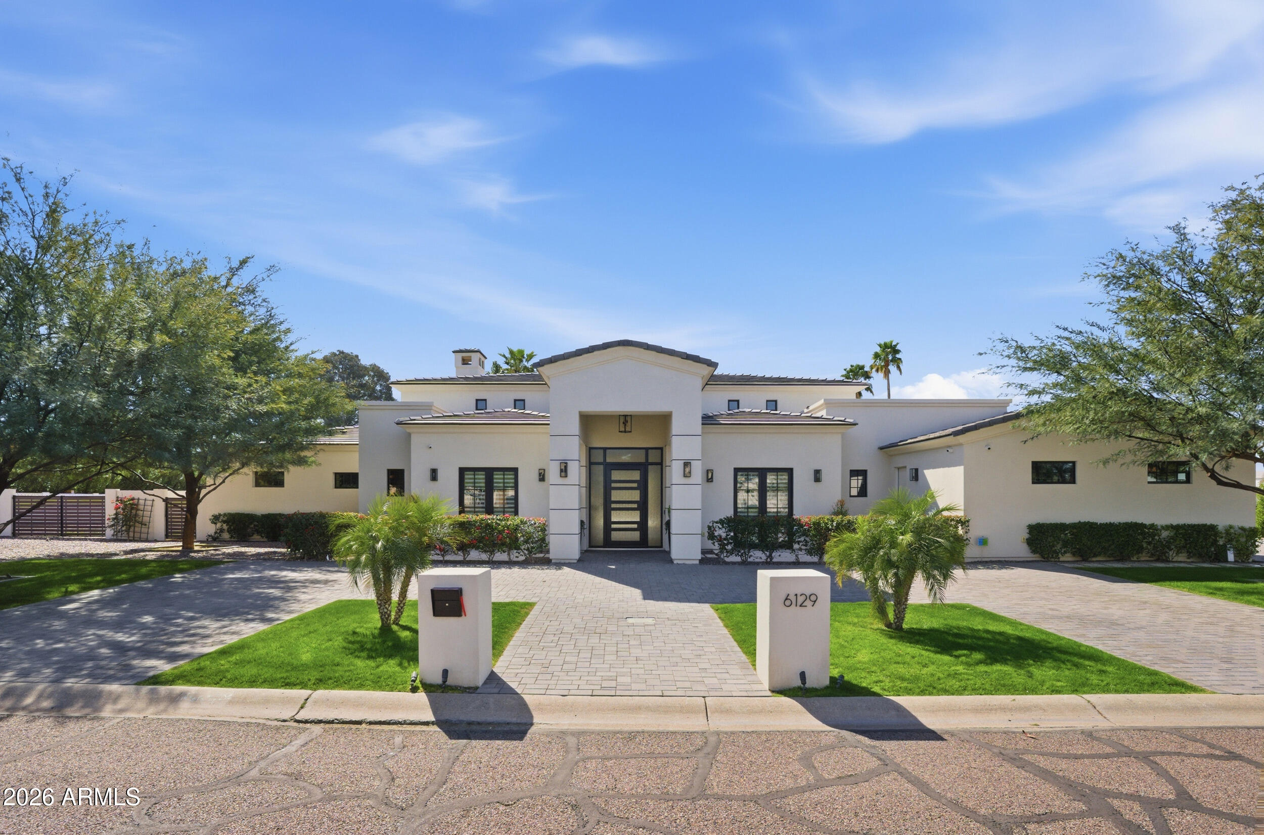 Exquisite single-level soft contemporary residence with soaring ceilings and an airy open-concept layout, offering stunning backyard views upon entry. The chef's kitchen features top-of-the-line Thermador appliances, including double ovens, two dishwashers, and a wine refrigerator. A refined split four-bedroom floor plan provides exceptional privacy with a guest wing, private sitting area, and a dedicated office ideal for remote work. The expansive primary suite is a serene retreat. A new Control4 smart home system seamlessly manages lighting, audio, climate and security with integrated cameras. Enjoy a resort-style backyard with mature palms, pool, Jacuzzi, waterfall, firepit, misting system, RV gate, and ample space for a future guest house--elevated Paradise Valley living at its finest.