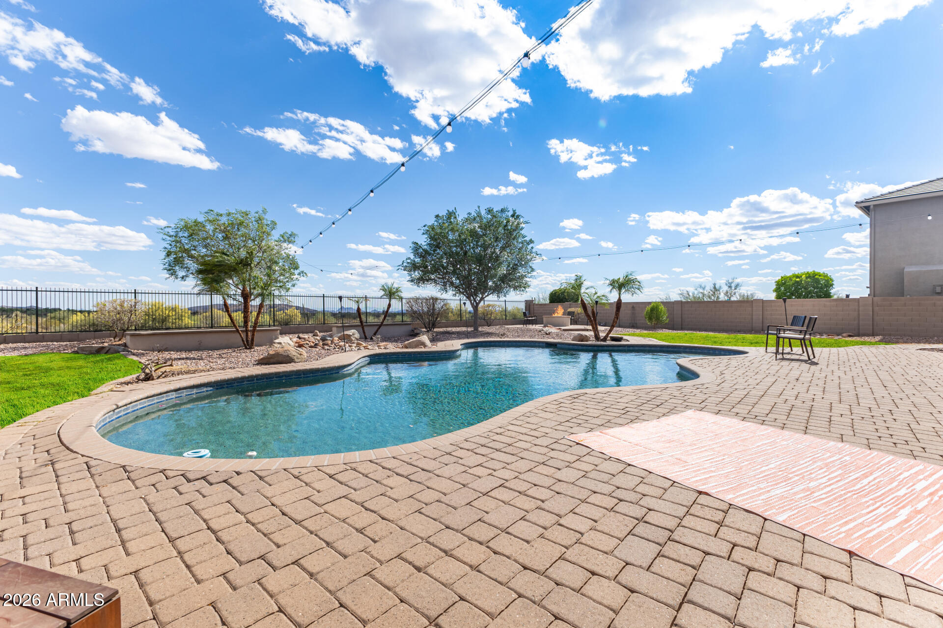 Amazing 5 BR+ home with sweetly tranquil Sonoran views and private cul-de-sac setting. Humongous backyard with 145' backing to an open wash area. A really cool play-pool, lawn (yes, a real one) and built in firepit is a special space for kids. Super OPEN kitchen features DUAL CONVECTION ovens, GRANITE  counters, gas cooktop, and Butler's pantry with wine fridge. Gas fireplace in the soaring ceiling great room. Classic formal living and dining room. Convenient office/den area. The home is a nicely split generational floorplan. The spacious MASTER is DOWNSTAIRS. Upstairs provides 3 Bedrooms+ and TWO baths with its own living/media/loft room area and walk out deck. Check out the deep 3 car garage, RV GATE. Solar (paid off by seller at closing) affordably shrinks the elec bill Downstairs main retreat is a private haven, complete with sliding doors to the backyard, surround sound speakers, & lavish ensuite w/dual vanities, soaking tub, tiled shower, & large walk-in closet. Built-in speakers also in patio, den, formal living room, garage, and loft. Upstairs, a fabulous loft w/built-in desk area & access to a private balcony provides additional living space! The laundry room boasts extra cabinetry & a utility sink. Relax in the charming front balcony! Entertainer's dream backyard comprises covered patio, sparkling blue pool, lush grass areas, cozy fire pit, shade trees, & a view fence framing the stunning desert/mountain vistas. Great location at a peaceful cul-de-sac! You don't want to miss this awesome opportunity!