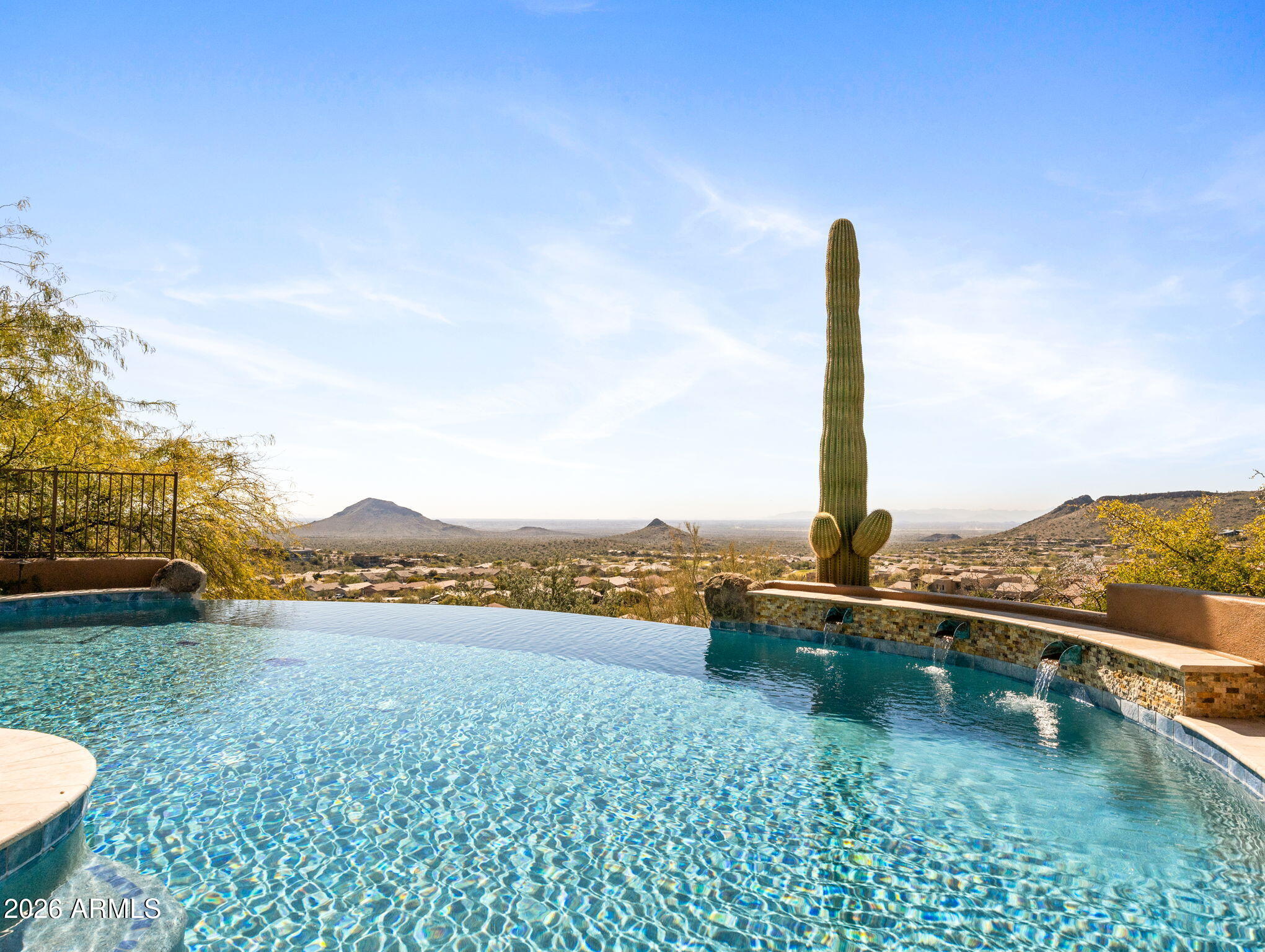 Perched high within the prestigious guard-gated FireRock Country Club, this meticulously maintained luxury residence invites you to surround yourself in panoramic views from every main living area, elevated above the sweeping valley below. Walls of tall butted-glass windows frame the desert, mountain, and city-light vistas while flooding the home with abundant natural light and seamlessly blending indoor and outdoor living.
The thoughtfully designed floorplan is anchored by a chef's kitchen that opens effortlessly to the family room and breakfast area, all oriented toward the deep covered patio and its breathtaking outlook. Culinary enthusiasts will appreciate the Wolf double ovens with 6-burner cooktop and griddle, Sub-Zero refrigerator, Sub-Zero 75-bottle wine cooler.  Elegant (Cont) Cantera stone accents, Barrel-vault ceilings, Cantera fireplaces and mantles, whole-house surround sound, and new custom shutters enhance the home's sophisticated character, while bamboo hardwood flooring warms the bedroom spaces.
Every bedroom offers the comfort of an en-suite bath, each appointed with Toto toilets and zero-entry showers. A spacious guest suite provides ideal accommodations for visitors or multigenerational living, delivering privacy without sacrificing luxury.
Step outside to a true resort experience. A newly finished negative-edge pool appears to spill into the valley views, complemented by new pool equipment, a heated spa, fire pit, putting green, and a wide variety of seating areas designed to capture Arizona's stunning sunrises and sunsets.
Additional highlights include two separate 2-car air-conditioned garages, all new HVAC systems installed in 2023, and impeccable pride of ownership throughout.
Residents of FireRock Country Club enjoy a celebrated 18-hole golf course, vibrant golf culture, and a sports club featuring a fitness center, tennis courts, and pickleball courts. A lively calendar of dining, social, and racquet events accompanies a comprehensive $29M community reinvestment  creating not just a home, but a refined desert lifestyle in one of Fountain Hills' most sought-after communities.