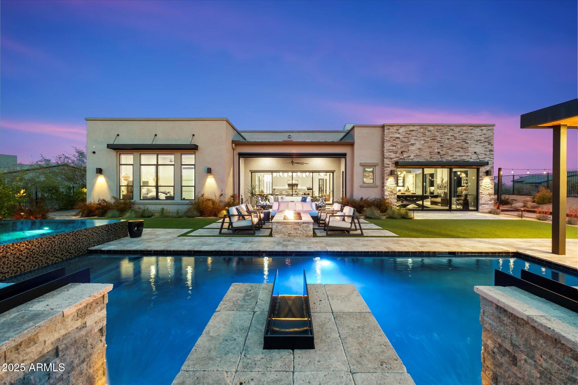 Discover the perfect harmony of elegance, warmth, and modern sophistication in this breathtaking 4,300 sq. ft. residence, tucked away in the prestigious gated community of Boulder Ranch by Toll Brothers with the Sonoran Preserve in the background.  Designed with impeccable attention to detail, this home showcases honed granite countertops, top-of-the-line SubZero and Wolf appliances, and a striking 400 bottle wine wall; a true showpiece for wine enthusiasts. Thoughtfully curated lighting fixtures enhance the inviting ambiance throughout.  The private and spacious primary suite offers a spa-inspired bath and a generous walk-in closet, while the attached casita provides a comfortable ensuite bedroom. A bright and stylish office, complete with a custom iron  barn door, creates the ideal work from home space.
Perfect for effortless entertaining, the open-concept kitchen flows seamlessly into the expansive great room, leading directly to a stunning backyard retreat. Here, you'll find a heated pool and spa, an outdoor kitchen complete with Lynx appliances including gas pizza oven, captivating fire features, and a bocce ball court. A spacious bonus room, complete with its own kitchen and bar with direct backyard access, adds even more versatility for gatherings.
With ample space to further customize your outdoor oasis, this move-in-ready home is a rare gem in a low-density community offering luxury, comfort, and immediate enjoyment (no waiting to build!). Ideally located just minutes from world-class hiking, mountain biking, dining, pickleball, tennis, Troon Golf, and the Rio Verde Country Club. Plus, enjoy breathtaking views of Troon Mountain, Tom's Thumb, and the McDowell & Superstition Mountains,a truly spectacular backdrop to this exceptional property.