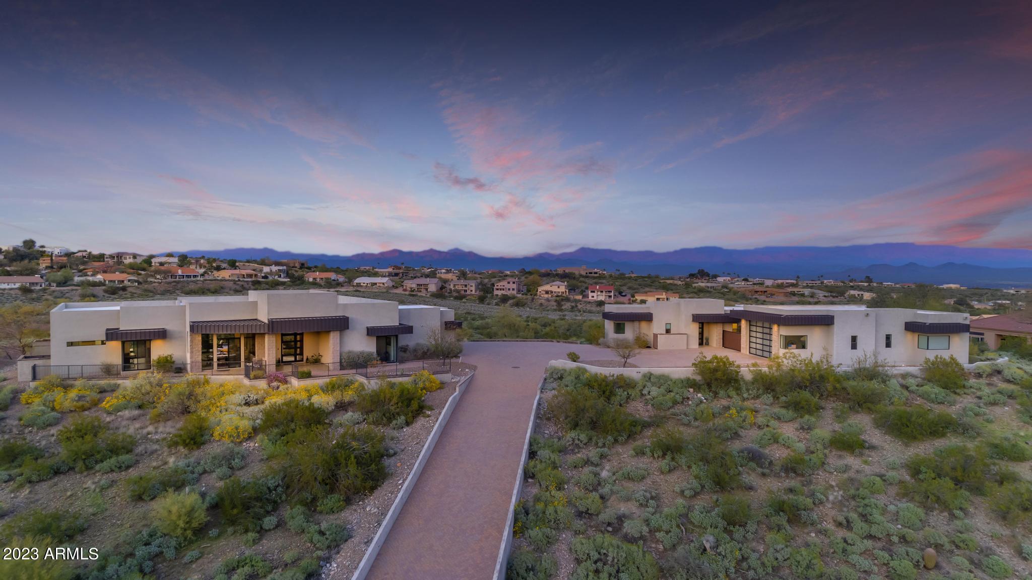 Welcome to your Fountain Hills dream! This exquisite hillside estate boasts 360-degree mountain views, showcasing the McDowell Mountain, 4 Peaks Mountain, and mesmerizing city lights. Nestled on over 2 acres, this light contemporary architectural masterpiece offers a harmonious blend of luxury and functionality. The main house features 4 spacious bedrooms and 3.5 bathrooms, with every window providing an unparalleled view of the surrounding landscape. The open concept living space is accentuated by a chef's kitchen, complete with Sub-Zero Wolf appliances, two dishwashers, a built-in wine cooler, and waterfall granite countertops. Gather around the cozy gas fireplace or step through the wall of glass to the covered patio, an ideal space for entertaining or simply taking in the breathtaking scenery. The detached guest house offers a world of possibilities, featuring a fully-equipped kitchen, great room, bedroom, bathroom, walk-in closet, washer and dryer, and a private patio with wall-to-wall windows for uninterrupted views. For the auto enthusiast or adventurer, this property features a spacious RV garage with dual glass garage doors, an RV gate, and ample storage for boats and toys, all finished with durable epoxy garage floors. The expansive paver driveway allows for plenty of parking, making this the perfect home for hosting family and friends. Step outside to your own personal oasis, featuring a heated pool with a water feature, built-in BBQ, and a vast array of outdoor living spaces to relax and enjoy the stunning panoramas. Architectural block touches throughout the property further enhance the contemporary design, creating a one-of-a-kind residence. Please note: Main house is 3345 sq feet and Guest house is 888 sq ft per tax assessor.
