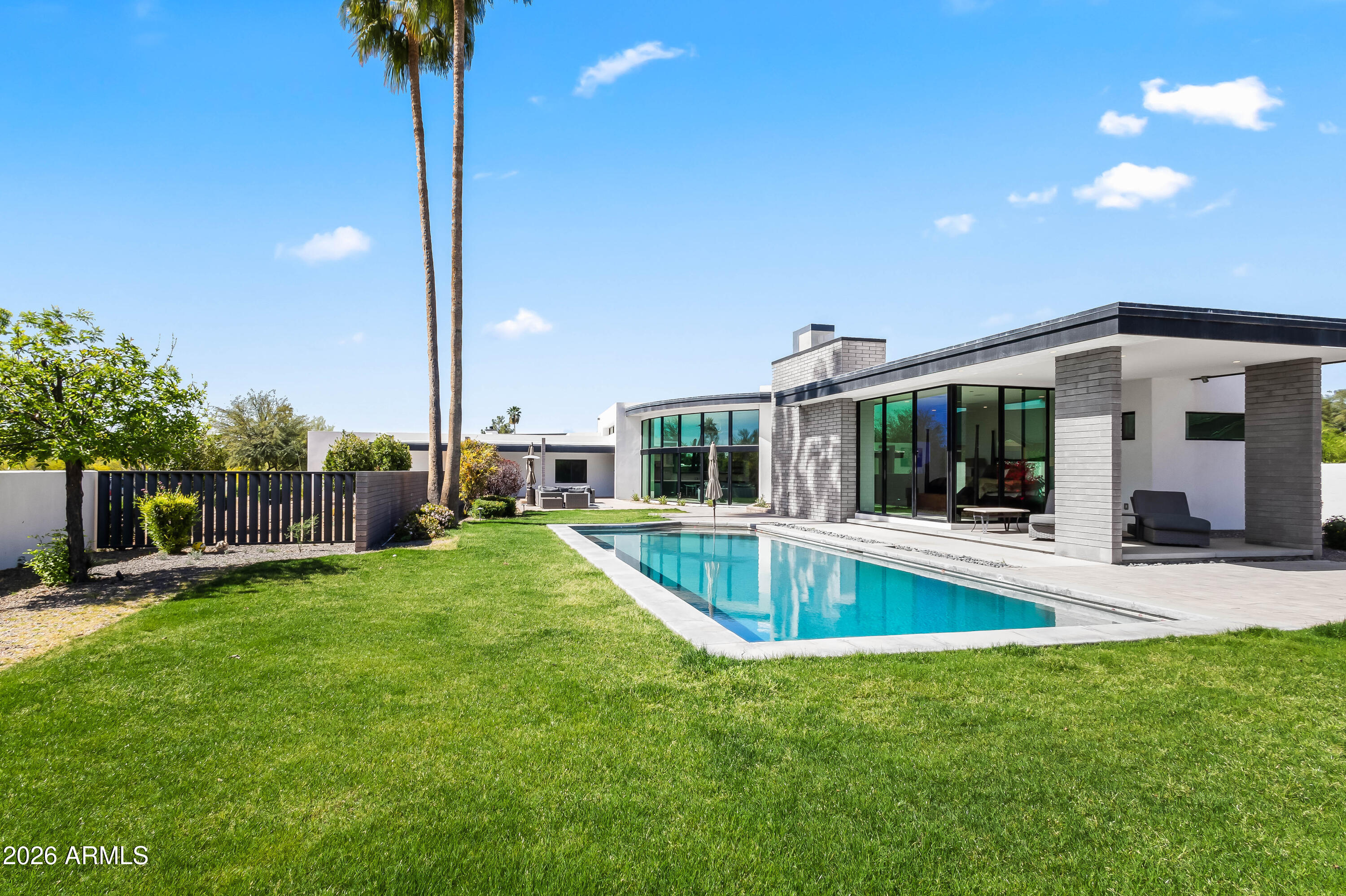 Located in the highly sought-after Hopi School District, this exceptional 5-bedroom, 4.5-bathroom home in the heart of Arcadia was design to blend modern and timeless luxury, framed with breathtaking Camelback Mountain views. Featuring soaring ceilings and a light-filled great room anchored by floor-to-ceiling custom windows and a striking two-way metalwork fireplace. European Oak flooring flows throughout, enhancing the open-concept layout that seamlessly connects the great room, living space, and chef's kitchen. The kitchen serves as the centerpiece of the home, featuring a large eat-in island, high-end appliances, custom floor-to-ceiling cabinetry, and a sleek wet bar with wine fridge. The primary suite offers a private retreat with stunning mountain views, expansive windows, cozy fireplace, and spa-like bath complete with dual vanities, an oversized shower, a soaking tub, and a spacious custom walk-in closet. The resort-style backyard is designed for both relaxation and entertaining, offering covered and uncovered patio areas, a custom pool, mature palm trees, and a large grassy yard--all set against a dramatic mountain backdrop. Additional highlights include a 3-car garage and a versatile bonus room ideal for a playroom, office, gym, or media space. Ideally located near The Global Ambassador, AJ's Fine Foods, and Arcadia's premier dining, shopping, resorts, and golf, this home delivers an exceptional lifestyle in one of Phoenix's most desirable neighborhoods.
