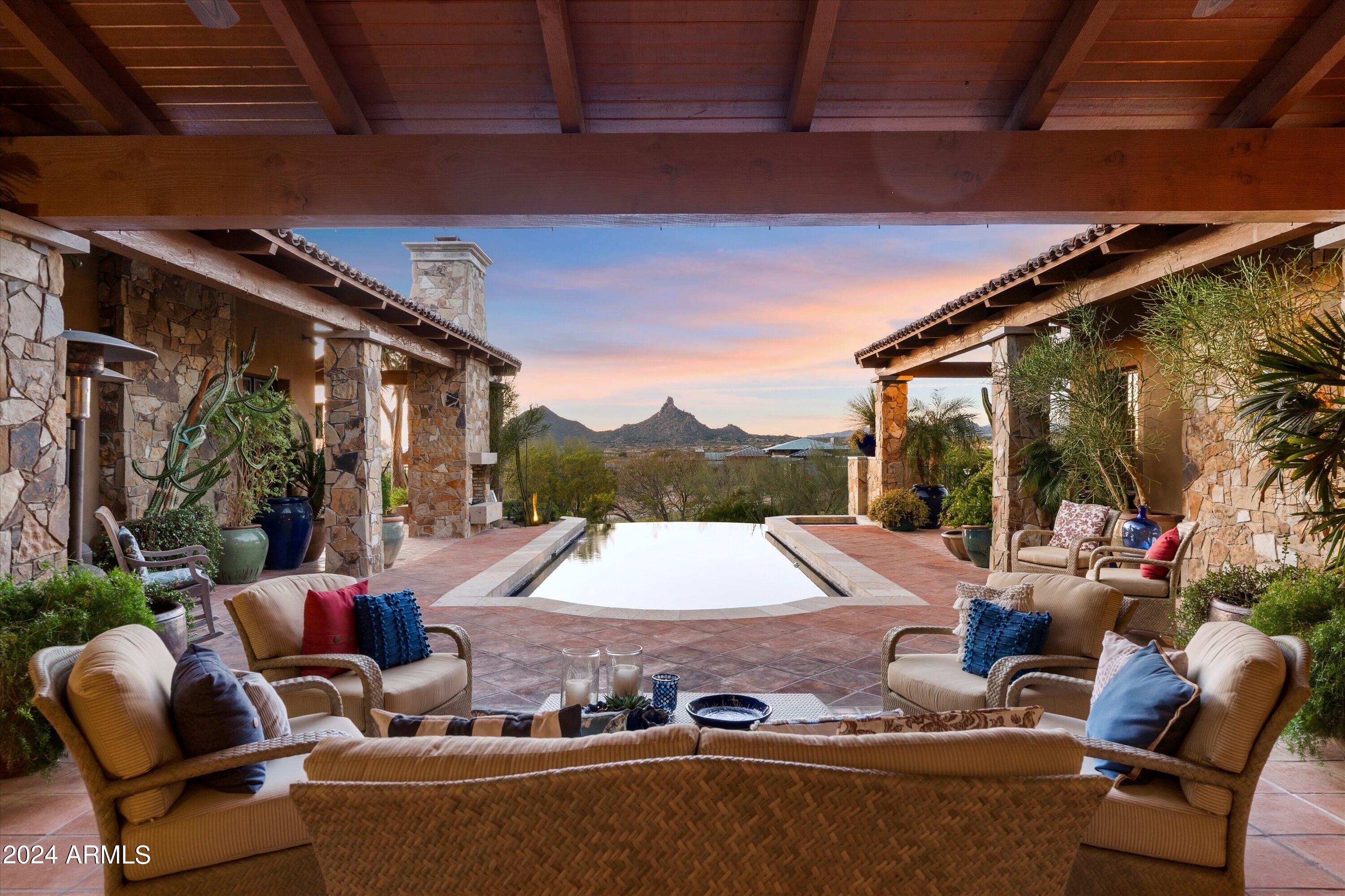 Experience architectural brilliance on a signature lot in Legend Canyon, a prestigious gated enclave of just nine homesites. This timeless masterpiece was designed by Architect Bing Hu. The interiors were curated by Janet Brooks, and inspired by San Miguel de Allende, in Mexico. Gracing a vast 3.39 acre parcel, it offers breathtaking views of Pinnacle Peak, the  McDowell Mountains, and twinkling city lights beyond. With a gourmet kitchen, hand-painted Italian tiles, and an esteemed office, the residence exudes opulence, easy living, and master craftsmanship. The great room overlooks the generous outdoor living spaces and dramatic Pinnacle Peak views, perfect for alfresco dining and year-round entertainment. Each bedroom boasts a dedicated patio, blending See its MOTION VIDEO indoor-outdoor living seamlessly. A must see detached Guest Home; this hacienda offers an unparalleled sense of livability and comfort, all while being set among tranquil and unforgettable backdrop views.