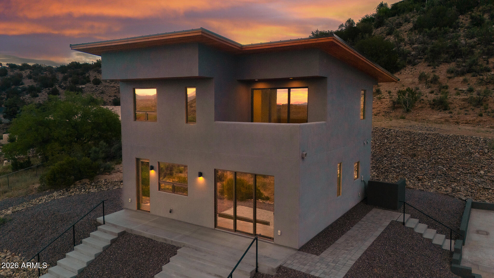 Come take in this beautiful modern masterpiece. This thoughtfully designed home offers 2 bedrooms plus an office, 2 bathrooms, and breathtaking views that stretch for miles. Perched on the hillside, the home is perfectly positioned to capture Arizona's stunning sunsets. Inside, you'll find a sleek and contemporary design featuring custom wood countertops, black cabinetry, stainless steel appliances, and polished concrete flooring on the main level. Both bedrooms are spacious and each connects directly to a bathroom, offering comfort and privacy. The bathrooms showcase elegant finishes, including floating vanities, custom lighted mirrors, and luxurious walk-in showers. The primary bathroom also features a large soaking tub, creating a spa-like retreat. The office is conveniently attached.. to the upstairs primary bedroom, making it an ideal private workspace. The exterior reflects a clean, modern aesthetic with synthetic stucco construction and a durable metal roof for long-lasting protection. Enjoy outdoor living with a private patio just off the primary bedroom, as well as a large paver patio and concrete driveway at the front of the home. Situated on just under an acre (0.96 acres), this property offers both space and style in a truly scenic setting.