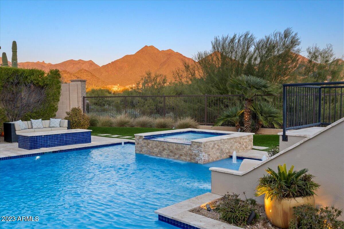 SPECTACULAR WINDGATE home showcasing the coveted McDowell Mountains in the backdrop!  Nearly all areas captures the magical mountain views!  This residence has been so highly cared for, timeless designer finishes from the entry gate of the courtyard to the resort like yard featuring newly updated heated pool, spa, color wheel, firepit, basketball court with low lights, turn (easy maintenance), putting green, slide, firepit and exterior cabana with televisions and misters!  Truly a custom home for this semi custom builder!  The main level offers primary, two generous offices (one with double doors), customized casita/full bath and private entrance.  One of the only retractable glass doors at great room ! The primary room frames the majestic mountains and extended the master closet bath (oversized).
The dining area opens to the court yard with rock backdrop of waterfall and accent lighting.  The spacious second level has room to grow and move!  Four oversized bedrooms, walk in closets and two shared baths with designer showers and hard surfaces.  There are desk built ins and a murphy bed!  STUNNING