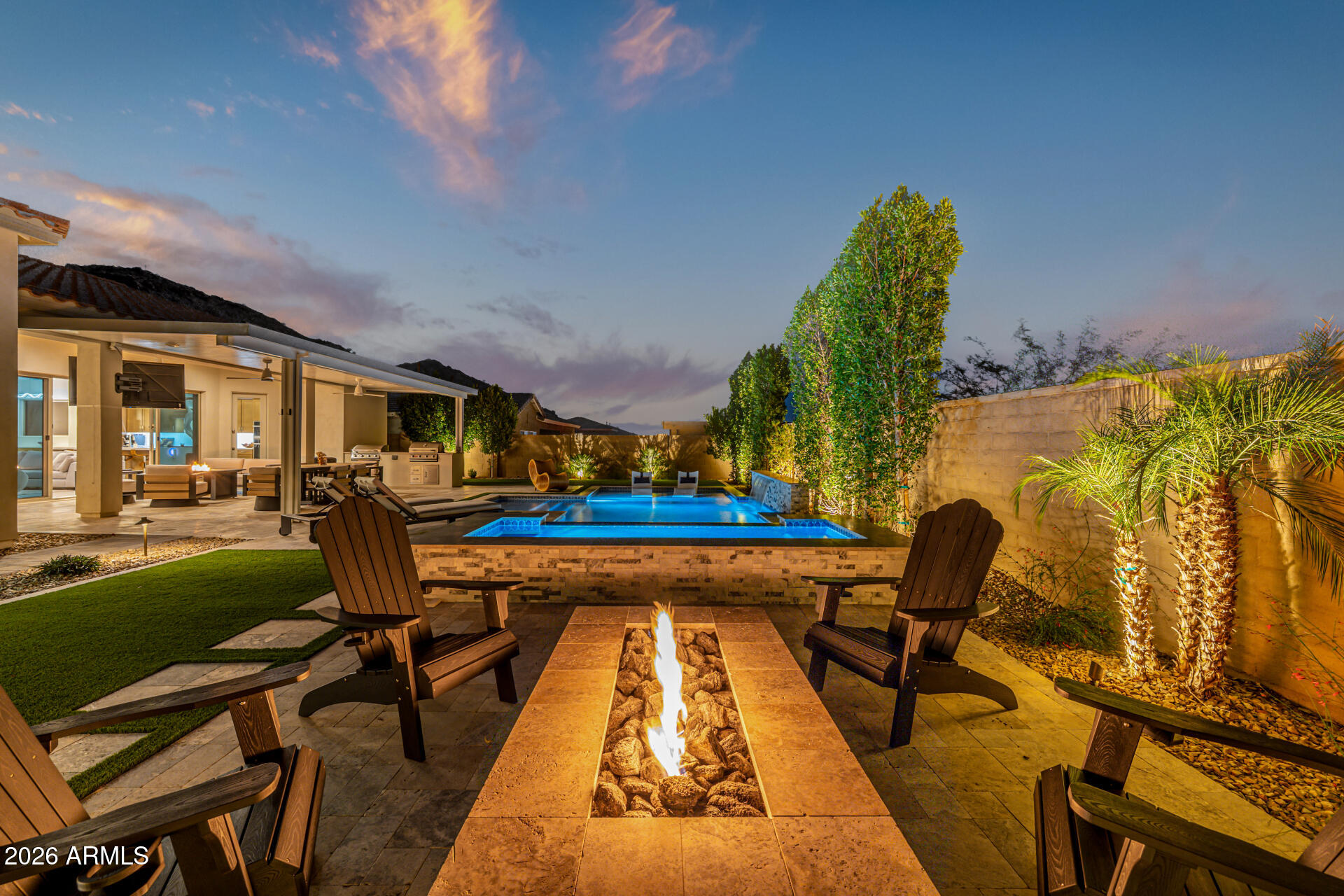 Impeccably designed 2024 home located in a gated David Weekley enclave in Verrado with over $200,000 invested in a custom resort-style backyard. This elevated 4-bedroom plus office/flex space, 3.5-bath residence blends luxury and functionality with tile flooring throughout and an open layout built for entertaining. The chef's kitchen showcases a waterfall quartz island, upgraded cabinetry, GE Monogram stainless steel appliances, generous pantry, and abundant storage, flowing seamlessly into the great room and out to your private outdoor retreat. Enjoy Arizona sunsets by your firepit, with views of the mountains.  Heated pool and spa, extended covered patio, pavers, built-in BBQ, make entertaining a breeze! 4-car tandem garage. Close to golf, trails, parks, dog park, shopping, and dining!