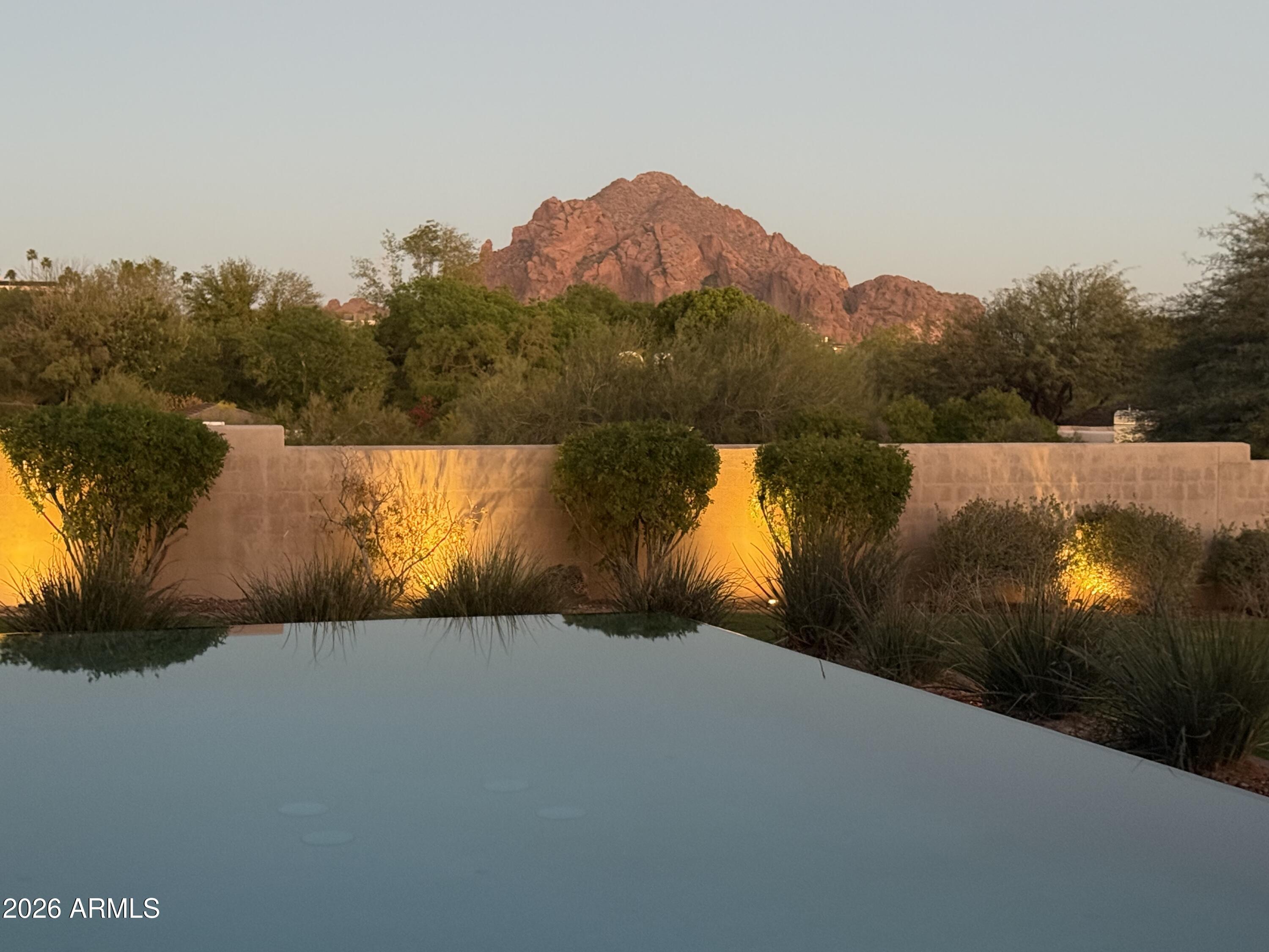 An elevated private estate on 1.48 acres located in one of Paradise Valley's most prestigious residential pockets. 360 degree sweeping views from Camelback to city lights. The 5050 sf main residence offers 4 en-suite bedrooms and a flex office/5th bedroom. The entertainers kitchen includes a Viking and Dacor appliance suite. Indoor/outdoor living shines with a grand covered travertine patio, outdoor kitchen, heated pool, spa, shower, rooftop entertainment deck, and space for a sport court or casita. AUTO ENTHUSIASTS will love having 2 separate garage locations: an attached 3-car and a large detached 3+ car garage w/lift and TV lounge. A Crestron smart home built with exceptional quality and intention. ESTIMATED $9M TO REPLICATE; Freshly painted interior. Thoughtfully conceived, meticulously built, and deeply cherished by its current owners, this residence offers exceptional structural integrity, a highly functional floor plan, and an irreplaceable setting. The location and views are truly one of a kind--elements that cannot be replicated--while the opportunity to refine and personalize the interiors remains entirely within reach.
The home has been lovingly cared for and has custom, high quality finishes that have years of fine life left in them. 
Some respected Paradise Valley/Scottsdale luxury custom home builders have toured the property and shared that constructing a residence of comparable caliber on this lot today would likely exceed $9 million and require well over a year to complete. This presents a rare opportunity to acquire a home of enduring substance and, if desired, reimagine it with your own bespoke vision--resulting in a distinctive estate that stands apart from the uniformity of today's new builds.
This is a property that discerning buyers will recognize as truly exceptional--one that others will wish they had aquired.

Buyers are advised to independently verify all details of personal importance.