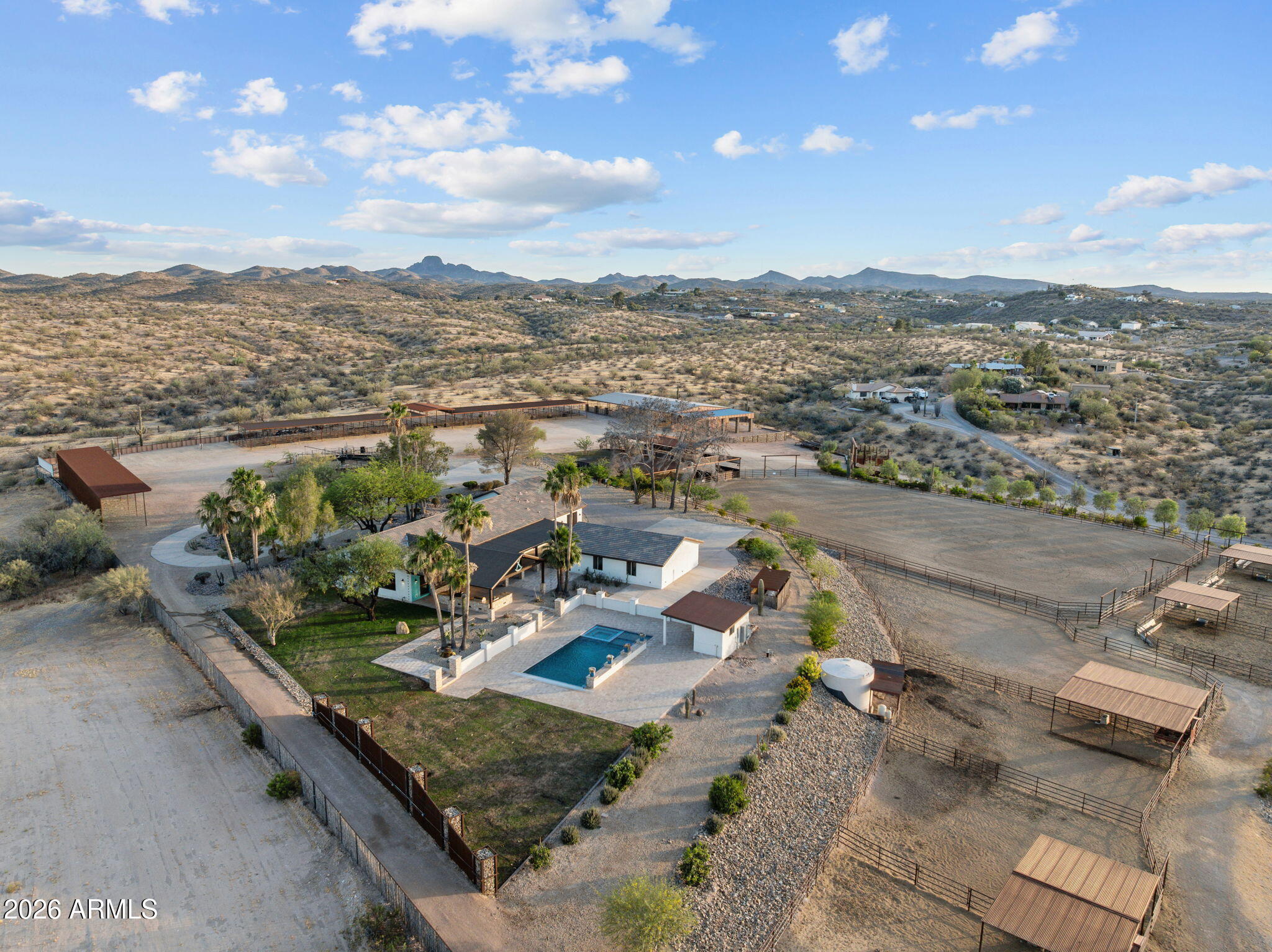 A gated coded entrance welcomes you to this exceptional equestrian estate backing State Land, offering a premier horse setup, luxury custom home, & resort-style outdoor living. The property is beautifully landscaped w/ decorative rock throughout & serviced by a brand-new private well producing approximately 30-50 GPM, along w/ a 13,000-gallon storage tank.Designed for serious horse enthusiasts, the property features a 150' x 285' roping arena w/ Chute Help & Priefert equipment, covered boxes, & a party pad overlooking the arena. Additional equestrian improvements include a 20'x40' tack room w/ saddle & bridle storage,wash rack, bathroom w/ shower, washer & dryer, storage beneath the arena w/ 50-amp service,  ++ more a Priefert 6-horse hot walker, (16) 50' x 30' horse pens w/ auto waterers + power, (12) covered 15' x 30' barn pens, 4 large turnouts behind the home, (4) steer pens, a 25'x60' pavered pad, & a140'x25' hay shed w/ shaving storage. The facility is serviced by 800-amp electrical service, arena & pens lighting, & sprinkler systems throughout the horse pens. Additional amenities include (4) 50-amp RV hookups & two RV parking spaces attached to the barn.The custom-built home showcases western elegance & quality craftsmanship w/ tile flooring, exposed wood beams throughout, copper & wood siding accents, sliding barn doors, a dedicated office with closet, powder room, security system, and two instant hot water heaters. The gourmet kitchen is designed for entertaining & features a Wolf gas range, bar sink, custom wood bar, & wood countertops.The spacious primary suite offers custom tile flooring, a steam shower, double vanities, & a separate toilet room. Guest accommodations include a Jack-and-Jill bathroom with double vanities and shower, an additional guest bedroom with a walk-in closet, and a second primary suite featuring double sinks & a split shower/toilet design.Outdoor living is equally impressive w/ a heated chlorine pool featuring a water feature, hot tub, travertine decking, outdoor kitchen, & a stunning two-sided fireplace beneath a covered patio accented w/ decorative tin. Additional improvements include a dedicated pool equipment room, underground propane system, and an oversized detached 3-car garage designed to accommodate dually trucks.Furniture may be available on a separate bill of sale, offering a rare turnkey opportunity for the discerning equestrian buyer.