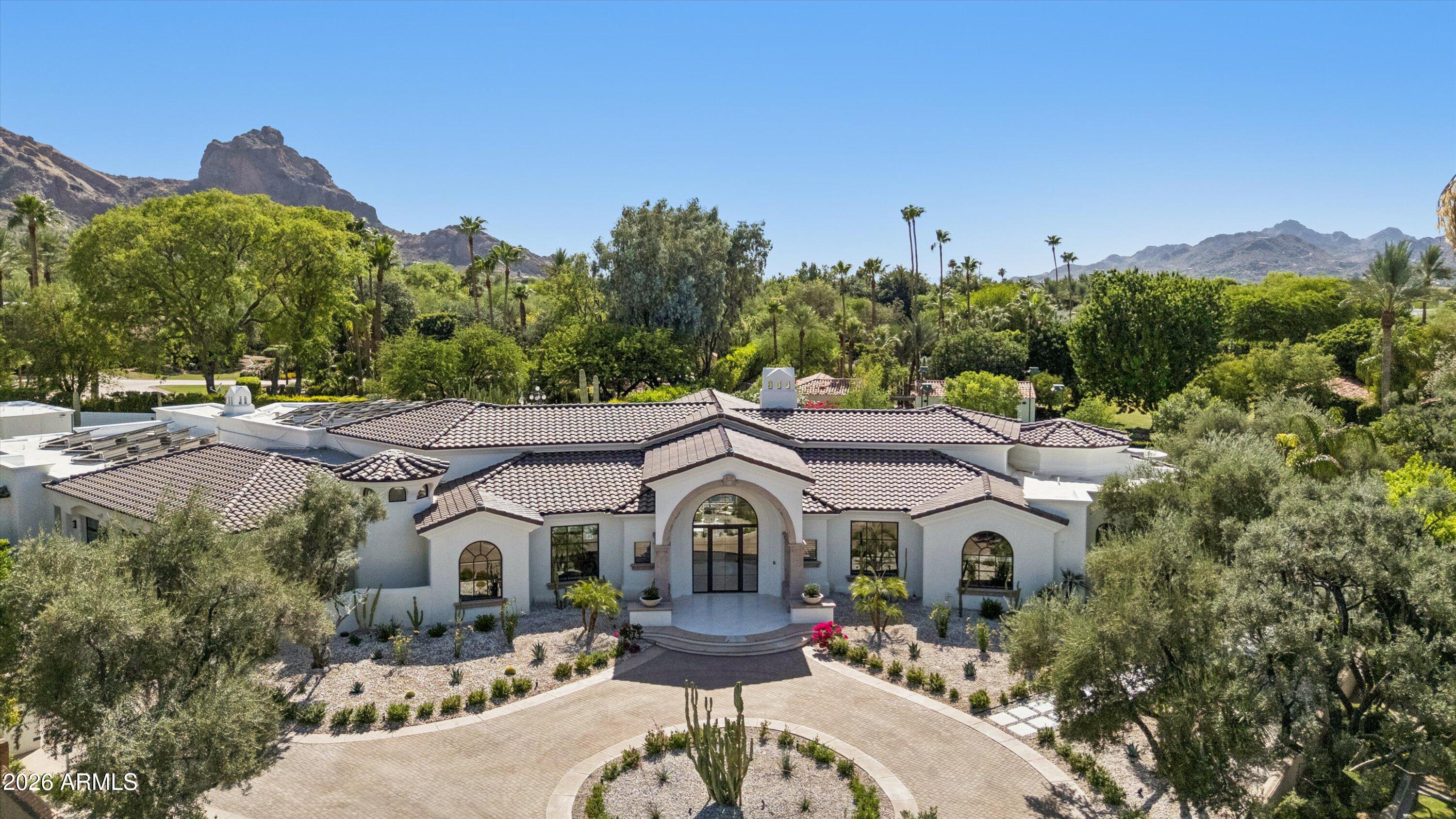 Rare opportunity within the 24/7 guard-gated Finisterre enclave, this extraordinary Paradise Valley estate offers 9,281 square feet of comprehensively reimagined luxury framed by iconic views of The Praying Monk, Camelback Mountain, and Mummy Mountain. Thoughtfully redesigned by emerging architect Yap-Chan of Arizona State University, the residence seamlessly blends refined modern design with timeless desert architecture, creating a private sanctuary defined by sophistication, wellness, and effortless indoor-outdoor living. Designed for grand-scale entertaining and intimate everyday living alike, the 7,586-square-foot main residence showcases expansive gathering spaces, soaring ceilings, museum-quality slab limestone, engineered white oak flooring, new energy-efficient windows and doors, integrated smart-home technology, whole-home water filtration, and an air-conditioned four-car garage. At the center of the home, an expanded chef's kitchen was curated for elevated entertaining, featuring dual islands, premium Miele and Viking appliances, and two walk-in pantries, all thoughtfully connected to elegant living and dining spaces. An inviting wine room offers a refined setting for collectors and intimate gatherings .Beyond the main residence, a detached guest house/casita provides luxurious accommodations for extended stays or multigenerational living. Resort-inspired grounds unfold as a private desert retreat, where sweeping mountain vistas frame expansive outdoor living spaces designed for both recreation and relaxation. A dedicated sport court, spa-inspired wellness retreat complete with steam room and private pool bath, and thoughtfully designed entertaining areas create an atmosphere reminiscent of a world-class resort. Offering exceptional privacy, architectural vision, breathtaking natural beauty, and seamless luxury living within one of Paradise Valley's most coveted guard-gated communities, this is a truly rare opportunity to own an extraordinary desert estate.