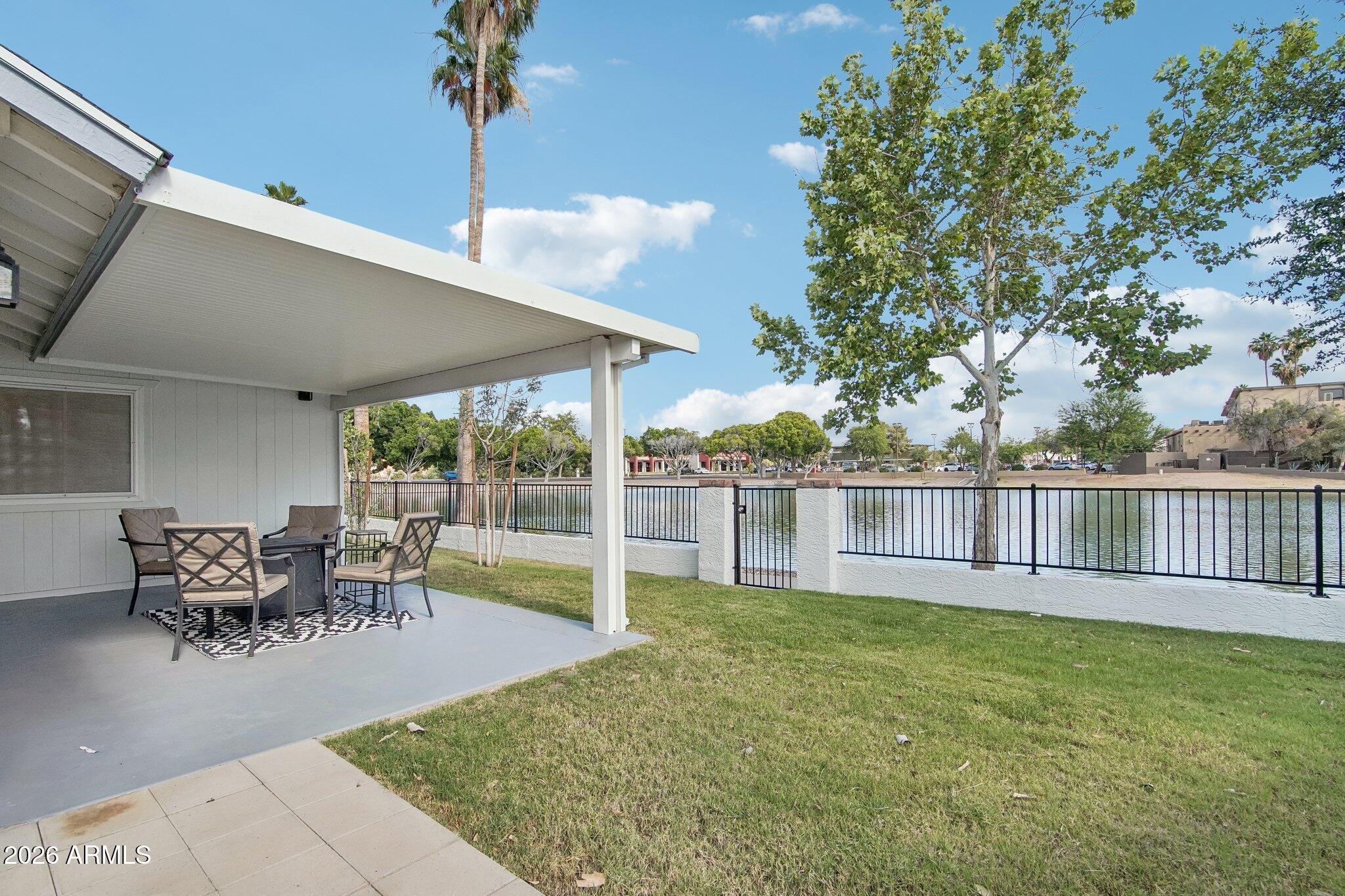 Enjoy peaceful waterfront living in this beautifully maintained Dobson Ranch home with breathtaking lake views and direct access to nearby walking and biking paths just outside the backyard gate. Designed for both comfort and entertaining, the backyard features a spacious paver patio, pergola for shade and ambiance, lush grass, mature trees, and established landscaping that creates a relaxing outdoor retreat. Inside, the home offers an open and functional layout with granite countertops, stainless steel appliances, updated bathrooms, and stylish wood-look plank tile flooring throughout. This rare waterfront property combines comfort, charm, and an unbeatable location in one of Dobson Ranch's most desirable settings. Enjoy beautiful sunsets and tranquil views right from your own backyard.