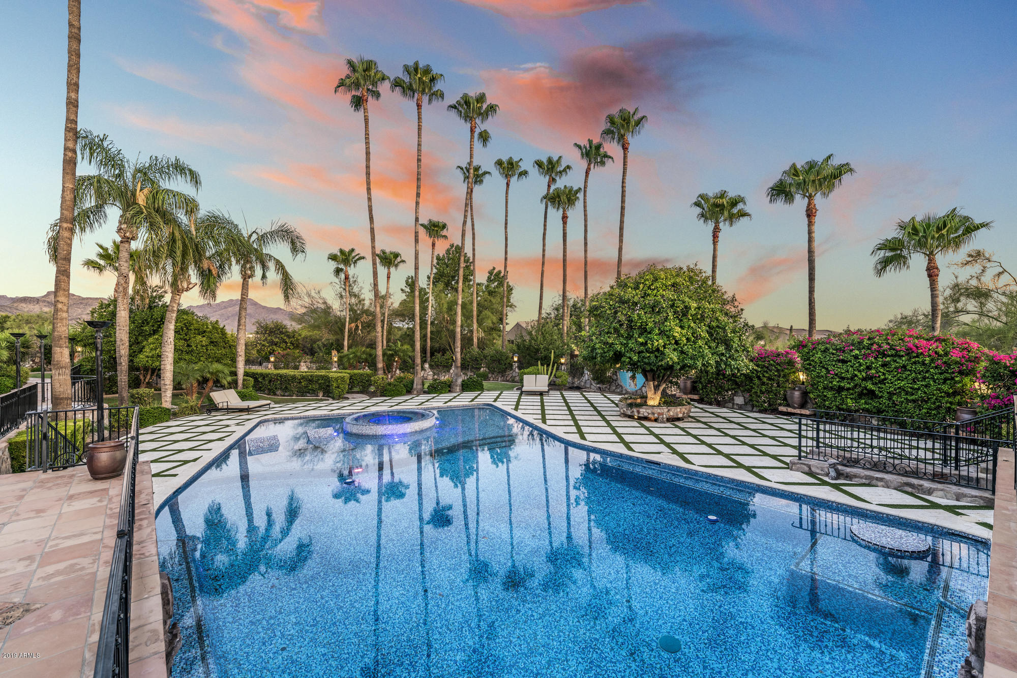 Own a piece of Arizona history in this fantastically charming masterpiece with a touch of celebrity . Akin to a boutique hotel, this exquisite Spanish- inspired estate has been lovingly restored with some modern touches. As you enter through your private gate, the tree-lined driveway will greet you with fountains, a romantic courtyard entry and bell-tower. Inside you will find 5 private en-suite bedrooms, hand carved mahogany doors, beamed ceilings, 120 ft grand hallway w/lighted brick arched ceiling, soap stone/leather granite counters, herringbone floors , a sumptuous parlor and more. Situated on 3 acres with city light  & mountain views, the lush grounds offer a myriad of recreational choices, from a private wine cave w/ dining area, an 1800 sq ft pool with over a million hand laid tiles, a covered resort- style bar and outdoor kitchen, bocce ball court , 6-hole putting green and private garden to read & reflect .

The 9 car garage offers a cantina & private patio where car enthusiasts can gather for hours, perhaps discussing how the home was originally owned in the 1970's by Andy Granatelli , the prominent businessman and CEO of STP, who was also a major figure in automobile racing events. Granatelli was known to hold lavish parties here and it's been said that many Hollywood faces graced the halls of this home, including the legendary John Wayne.