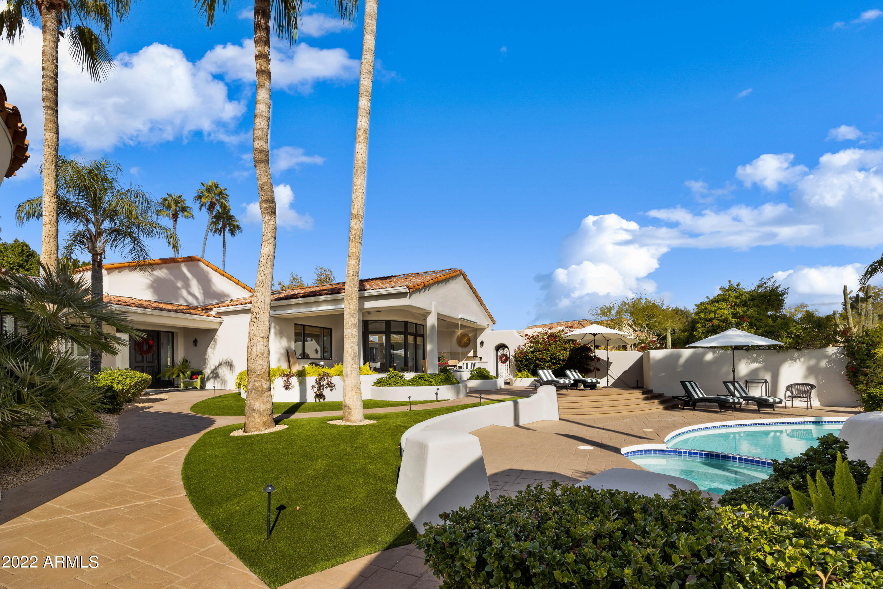 Quintessential custom retreat situated on the 18th fairway of the iconic Pinnacle Peak Country Club golf course, awaits the most discriminating buyer that will appreciate and enjoy this completely remodeled four-bedroom, four-bathroom home including soaring beam ceilings, wood flooring throughout, split primary bedroom suite, guest retreat, dual offices, exercise room, tandem four car garage. The great room open living spaces offer serene vaulted beam ceilings, custom chandeliers and cozy gas fireplaces.  The owners have respectfully adhered to the original character and charm of the original home, while modernizing the home implementing inviting open and light spaces, modern kitchen, updated countertops and custom cabinetry, high ceilings and updated bathrooms offering modern, more Updated tile and stone including marble, updated plumbing fixtures and lighting. A light and airy updated kitchen offers high-end stainless-steel appliances, gas cooktop, center island, custom cabinetry, quartz counters and expanded views overlooking the outdoor living pool and McDowell mountains. The guest house is so inviting your guests might never leave! Offering a kitchenette, bath and sitting area with views of the 18th hole, this attached separate entry guesthouse is perfect for a weekend stay or a long visit.  The four-car tandem garage offers ample space as well as a large air-conditioned storage space or additional office for the home.  Come enjoy the North Scottsdale lifestyle in coveted Pinnacle Peak Country Club!