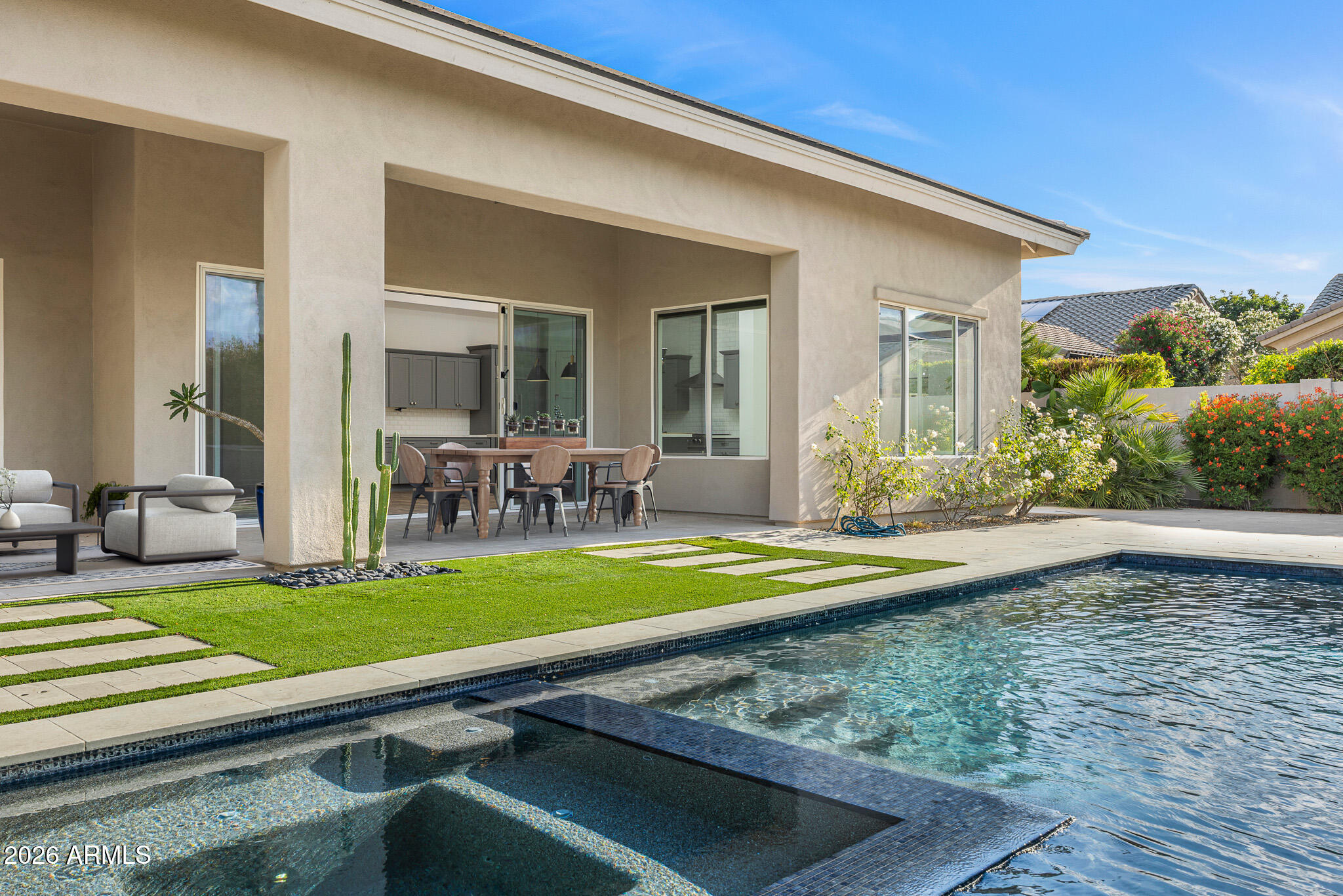 The ultimate lock-and-leave retreat in Paradise Valley, this beautifully designed residence is tucked within a quiet, private community and framed by mature ficus trees that create a serene, resort-like backdrop. Thoughtfully designed for effortless living, the home offers complete privacy, refined modern finishes, and an abundance of natural light throughout. Soaring ceilings and expansive windows elevate the interiors, while the elegant dining room flows seamlessly into a spacious open-concept family room that connects to the kitchen and sunny breakfast nook—ideal for both everyday living and entertaining. The chef's kitchen features high-end appliances, custom cabinetry, and a generous eat-in island designed for gathering. The primary suite is a true sanctuary, overlooking the pool and offering a stunning designer bathroom along with an exceptionally large walk-in closet with custom built-ins. The two additional bedrooms, bonus space, and 3.5 bathrooms provide flexibility for guests, family, or a home office. Outside, the private backyard is an entertainer's dream, complete with a sparkling pool accented by cascading water features, a large covered patio, fire pit, and ample space for outdoor dining and relaxation. Effortless, elegant, and impeccably locatedthis Paradise Valley home delivers luxury living with lock-and-leave ease.