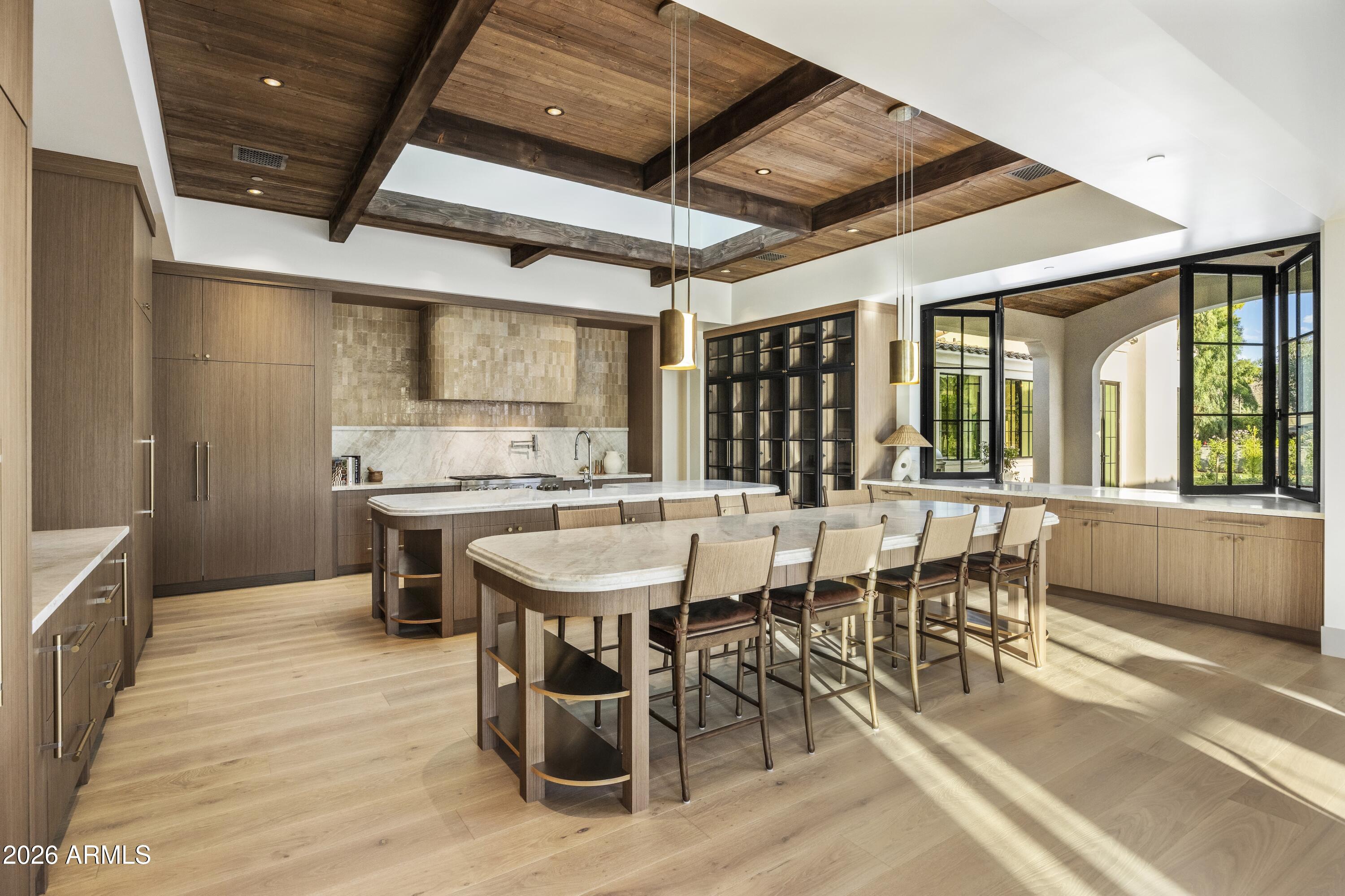 Now complete, a newly built Paradise Valley estate unlike anything currently on the market. Defined by warmth, depth, natural materials, and a level of comfort rarely achieved in new construction, this residence reflects a subtle sophistication felt intuitively the moment you enter. Thoughtful construction standards include 2x6 sound-insulated walls, solid 8-foot doors, 10-inch wide-plank oak flooring, curated natural stone and tile selections, honed Taj Mahal quartzite double islands, matching Taj Mahal mitered stone fireplace detailing, and 8-inch cove base--all contributing to a cohesive sensory experience created through an extraordinary collaboration of architecture, interior design, and craftsmanship.  Situated on 1.18 acres with no HOA in the coveted Came Elementary Corridor, this single-level estate seamlessly integrates indoor and outdoor Arizona living through soaring 17-foot exposed wood-beam ceilings and fully retractable walls of glass recessing into pocketed walls opening to a covered outdoor living pavilion overlooking the Presidential pool and spa. The double-Taj Mahal island chef's kitchen features Sub-Zero and Wolf appliances, a fully equipped butler's pantry-dirty kitchen with additional Wolf ovens and Cove dishwasher, and a dining room anchored by dual Sub-Zero wine towers. A sideboard allows guests to help themselves with crushed ice and beverage drawers, in addition to a large sit-up continuous slab pass-through window to the wood-clad covered BBQ Pavilion. All bedrooms are ensuite. Primary wing is split with private wellness courtyard. Guest parking in front, with privately gated resident's paved driveway to the side entry auto court, with 4 car garage expandable to 8. Even the laundry room has been elevated with brick floor, Burdette cabinets and mountain views! 
A distinguished collaboration by Tiara Sun Development, architect Jim Blochberger (recipient of the 2025 Master of the Southwest Award), and Evon Fig Interiors.
Designed as a fully integrated living environment, the home balances architectural presence with everyday livability. Wood-beam ceilings, handcrafted finishes, curated lighting, and a layered natural material palette create warmth, continuity, and enduring timelessness throughout.
This is not simply a home--it is designed to restore, perform, and endure. Designed as a fully integrated living environment, the residence prioritizes wellness, livability, comfort, and enduring design through natural materials, acoustic calm, seamless indoor-outdoor living, and thoughtful construction standards rarely achieved in new construction. The result is more than shelter--it is a home designed to enhance how life is experienced every day. ORGANIC-LUXE" has arrived in Paradise Valley.
See full specification sheet. Disclosure: Listing agents hold ownership interest.