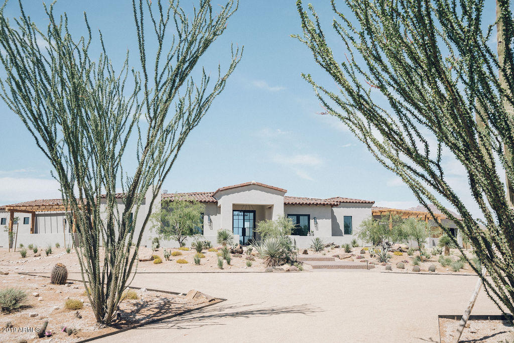 Modern Nest has done it once again, but this time with a custom build spec home situated perfectly on 3 acres in the heart of North Scottsdale. Their build + design team took the finishes to the next level and created an earthy and refined, modern Spanish desert home that you must experience in person. This home was built to maximize the mountain views from both the front and back yards. The front includes a large driveway to a four car garage area, parking pad at steps which lead you to the front entry featuring dual courtyards with a fireplace, landscaping designed to mimic the natural desert using mature plant selections so the yard doesn't look as new as the home. Natural materials and an earthy color palette keeps this home authentic to the surroundings while feeling clean and modern. Natural woods, natural stones/stonework and tons of beautiful, natural lighting makes this home feel warm and inviting. A huge kitchen/living area creates the main gathering space. Kitchen includes Wolf/Subzero appliances, top of the line lighting and faucet fixtures, incredible English White Oak cabinetry and an oversized waterfall island. A full butlers pantry off the kitchen adds even more storage space and function. Natural reclaimed beams line the towering ceilings in the main room, Roman clay walls add warmth and texture, a massive fireplace anchors the one end, while three sets of glass and black iron french doors to the back yard create, stunning Pinnacle Peak views, drama and design perfection. Full guest quarters/media room includes a private entry, kitchenette space and backyard access creating privacy and comfort. Large laundry/mudroom with custom cabinetry and cubby spaces will help keep any busy family organized. All of the home's 5 bedrooms (as well as the office) are ensuites with doors to outside and several with private patio spaces. The master suite, in its own wing, features incredible mountain views and a large bathroom with separate vanities, separate shower entries, separate toilet closets and a large free standing tub. The master closet is stunningly beautiful with custom builtins in English White Oak and convenient washer/dryer hookups. Off the master closet/master bedroom is a space with a coffee bar. This room could be used as a home office, work out space or a newborn nursery. The possibilities are endless. High end lighting selections throughout the home add clean lines and rustic touches. Lastly, the backyard has panoramic mountain views, brand new pool with an elevated spa/water feature, large grass areas and ample privacy. Travertine flooring throughout the enormous patio with a fireplace creates the perfect entertaining space. Don't miss the opportunity to see this home in person.