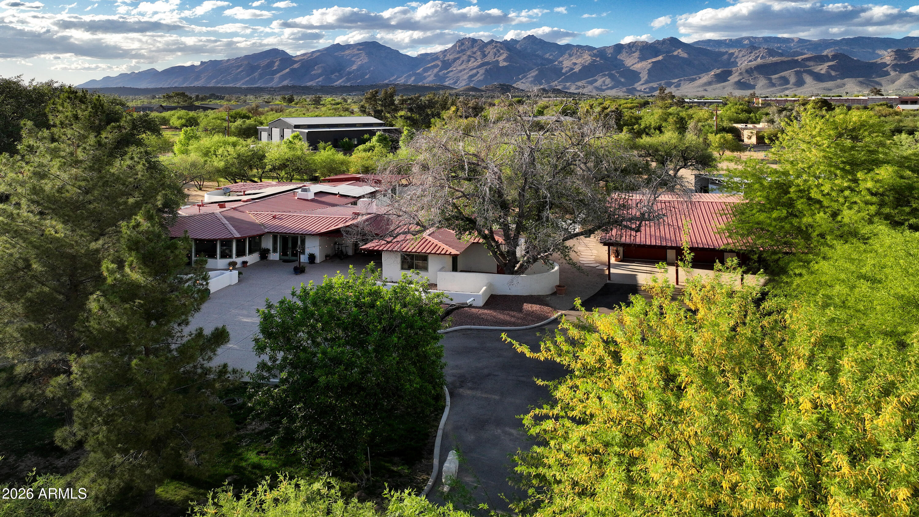 This truly magical ranch hacienda is a once-in-a-generation offering on the highly treasured Woodland Road in the heart of the lush Tanque Verde Valley. It is set apart from anything typically found in or around Tucson. Greeted by a beautiful gated entrance with a long meandering paved drive through towering mature trees and verdant pastureland, creating a sense of arrival that immediately conveys seclusion, serenity, and rarity. Here, the landscape feels almost otherworldly--cool, green, and timeless--yet remains remarkably close to the conveniences of town. The masonry residence encompasses 5,031 square feet of refined Southwestern elegance, thoughtfully designed for both gracious living and an intimate retreat. With five bedrooms and four baths, the home offers generous scale without sacrificing warmth. A true chef's kitchen with a large island anchors the living spaces, while three fireplaces add character and ambiance throughout. Multiple patios extend the living experience outdoors, framing spectacular mountain views and inviting year-round enjoyment of the exceptional desert climate. A sparkling pool and spa complete the resort-like atmosphere, ideal for both entertaining and quiet reflection.
Automobile and hobby enthusiasts will appreciate the exceptional garage capacity, with two separate garages accommodating up to ten vehicles--an uncommon and highly valuable feature. Equally impressive are the equestrian facilities, which rival those of much larger ranches: a well-appointed three-stall barn with individual large turnouts, a tack room with a convenient half bath, a large riding arena, round pen and a dedicated hay barn. Every element has been carefully considered for both functionality and comfort.
All of this is set on an extraordinary seven acres--land that is virtually impossible to replicate in this region. There are very few larger horse properties in town. This parcel has actually been subdivided into two 3 plus acre parcels, each with its own address for possible future building. Five rich, grass pastures are surrounded with classic pipe-rail fencing and irrigated by an excellent private well with coveted Irrigation Grandfathered Water Rights. Massive shade trees provide a park-like setting, while a fantastic, well built treehouse adds a touch of charm and nostalgia rarely seen in properties of this caliber. With no HOA restrictions, the estate offers true freedom of ownership.
This is the best of all worlds: extreme privacy, clean country living, and a pastoral environment that feels far removed from the city--yet only five minutes from dining, shopping, medical and everyday amenities. This is a property of profound beauty and tranquility, offering a lifestyle and setting that is simply not available elsewhere in the Tucson area.
