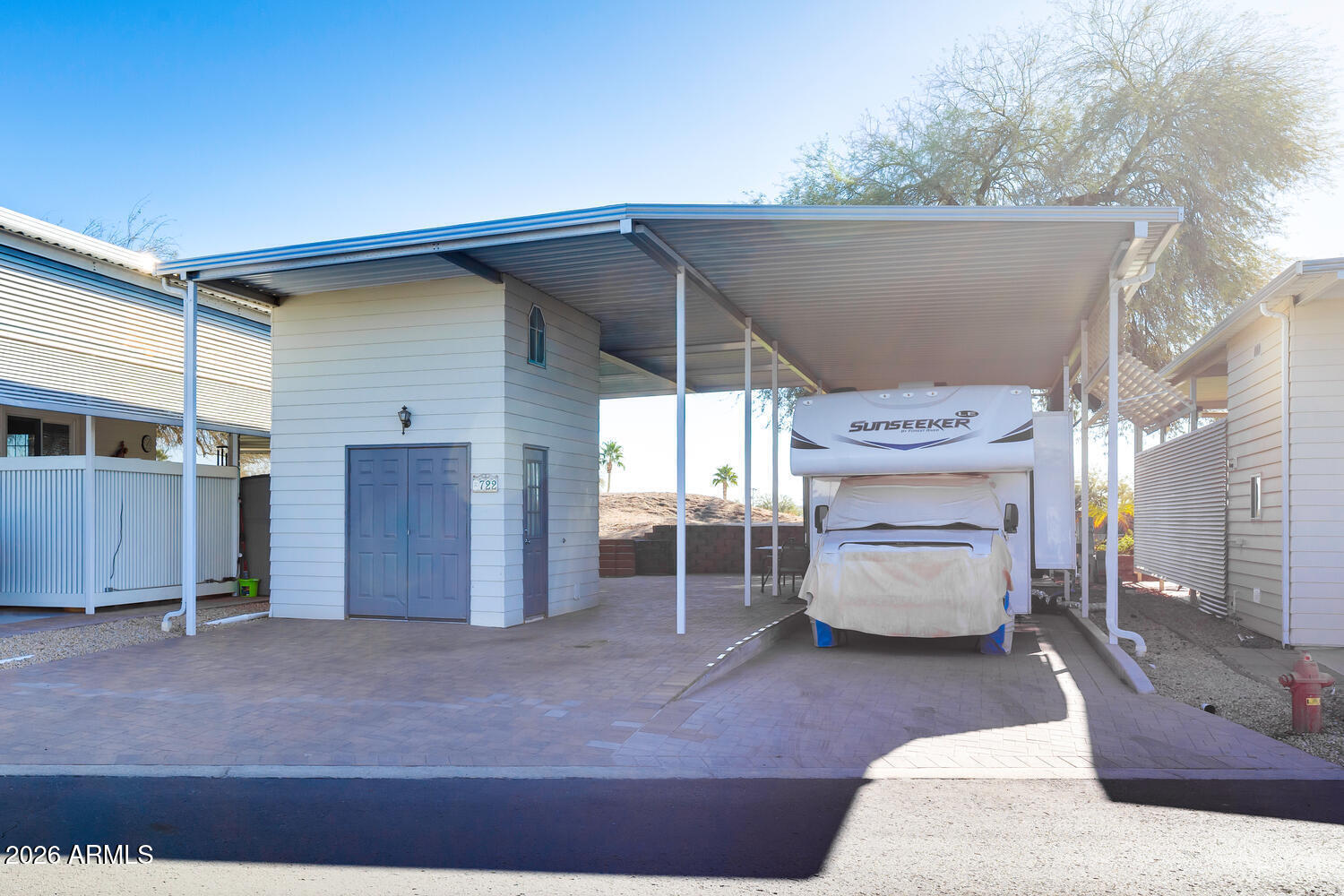 This RV lot checks all the right boxes.  Beautiful golf course view - yes. Very few available in Happy Trails. A fully covered lot with 13ft 8' awning for complete protection for your home on wheels.  Privacy fence on both sides so you can enjoy your home without prying eyes and entertain in quietness. And check out all the pavers on the entire property. Stunning!!!!!  A two story shed with all the essential perks. Newer W/D(2024), a great handy sink with spacious countertops. A frig for all your extras and best of all it has and enclosed toilet. The flooring is luxury vinyl for that classy look and  the upstairs if finished for a great storage area.