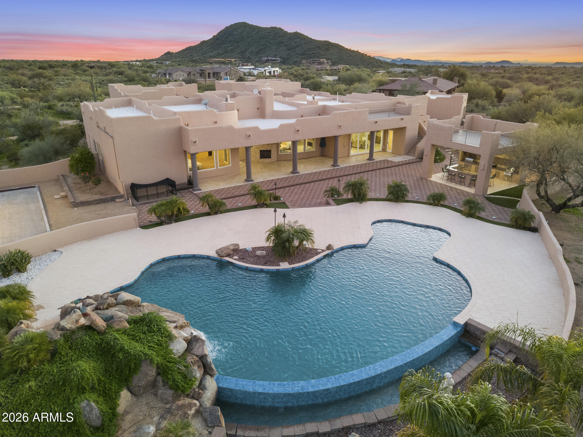 Priced $259K Below Recent Appraised Value! Experience Elevated Desert Living in this Custom Southwestern Estate set on nearly 3 Private acres in a Premier North Scottsdale setting, with stunning Mountain & Sunset Views. The 4,859 sq ft main residence is complemented by a 983 sq ft detached Casita, ideal for guests or extended stays. A Gated Entry leads to an expansive Paver Drive & exceptional Garage amenities including an attached extended-length 3-car Garage + RV Garage + 1 Detached Garage, accommodating up to 8 vehicles. Inside, polished Travertine floors, newer Custom Windows, Illuminated Recessed Ceilings, and a 2-way Fireplace create a Refined Ambiance. Resort-style grounds feature a dramatic Elevated Pool with Waterfall, Grotto, Hidden Slide, Outdoor Kitchen with View Deck, Fireplace, Patios & Bocce Court - perfect for Luxury Entertaining! - Designed for Elevated Living and Grand-Scale Entertaining, this Estate blends timeless Southwestern architecture with Modern Luxury. The Open-Concept layout seamlessly connects Formal and Casual spaces, Enhanced by Abundant Natural Light, Illuminated Recessed Ceilings, and Refined Finishes throughout. The Fully Reimagined Chef's Kitchen is a Showpiece, offering a Large Center Island, Granite Countertops with Full-Height Backsplash, custom Flat-Panel Cabinetry with Integrated Display Niches, Over & Under-Cabinet Lighting, and Premium Sub-Zero and Wolf Appliances including Professional Built-in Refrigerator/Freezer & Wine Storage, Wall Ovens, Convection Cooktop, Prep Sink, and Peninsula Seating. The two bar areas and formal handcrafted built-in dining hutch feature stunning, distinctive quartzite countertops. The Primary Suite is a Private Retreat Featuring a Fireplace, Motorized Blinds, Custom Built-in Wardrobe and Entertainment Unit, and a Spa-Inspired Bath with Soaking Tub, Spacious Walk-in Shower, Dual Vanities, and Expansive Custom His-and-Hers Closet Systems with Island Storage. Secondary Baths reflect the same Elevated Craftsmanship and Design including Marble Counters. Outdoor Living Rivals a Private Resort with an Elevated Pool, Oversized Waterfall, Grotto, and Concealed Slide! A Freestanding Gazebo offers an Upper-Level View Deck and a Fully Equipped Outdoor Kitchen below with Multiple Grills, Range/Oven, Fridge, Bar Seating, Ceiling Fans, and TV. Additional Covered Patios with Travertine Flooring and Fireplace extend the Living Space Outdoors, while a Bocce Ball Court completes this exceptional North Scottsdale offering!