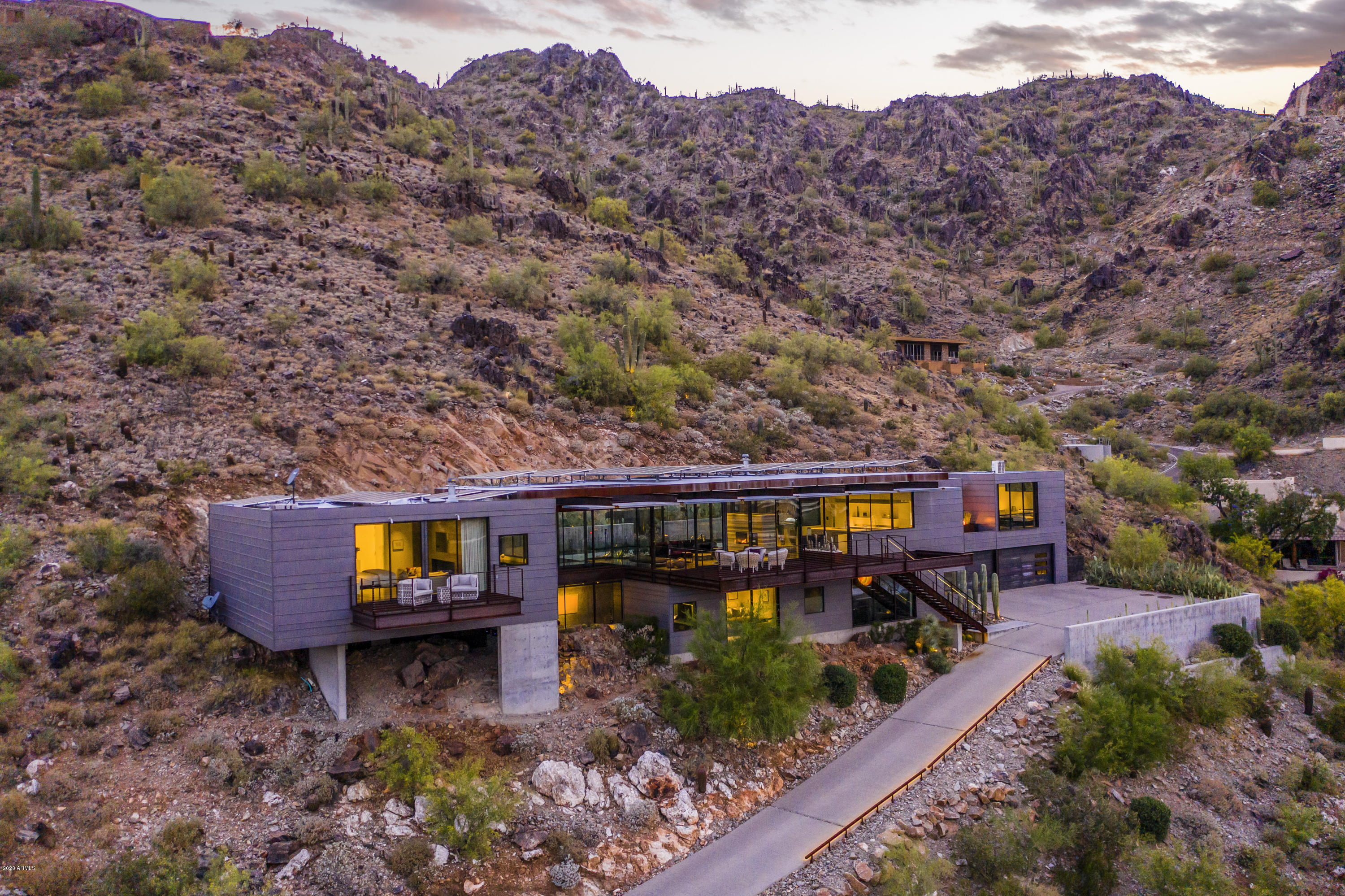 Elevated high on the Phoenix Mountain Preserve, in the guard gated community of Clearwater Hills, sits a steel, glass and concrete home designed and built by Construction Zone.   Walls of glass provide endless views of the valley below, sunrises, city lights, Camelback mountain and beyond.  The chef's kitchen and butler's pantry feature Miele appliances,   Poggenpohl cabinetry and Silestone quartz counter tops.  The dining and family rooms are entwined with an elegant, two-way, marble fireplace.  Walk across the glass bridge to enter the master suite, with a private terrace, steel fireplace, his and her walk in closets, and master bath with indoor/outdoor shower and top of the line Hansgrohe Axor Uriquiola bathroom fixtures. Outdoors, the private retreat welcomes you with a heated lap pool and spa, two sitting area, fire features, and built in bbq. As well as, the luxurious, private casita with a wall of glass offering your guests the same infinite views.  From the 4 car garage, enter directly into the lower level with 2 additional bedrooms, media room, game room and art gallery. A wood paneled elevator or the warm wood staircase, await to take you to the upper level.  Owned, Green Earth Energy Solar panels.  Additional energy efficient features include new programmable roller shades and LED lighting throughout.