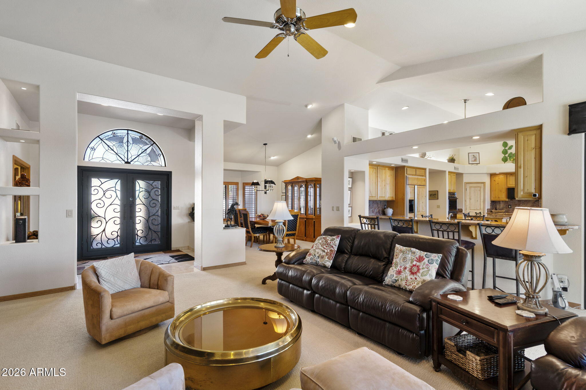 Gorgeous single-level home with outstanding views and great curb appeal. Enjoy Fountain and Four Peaks views from the front and Red Mountain and canyon views from the back, all on a private lot backing to a wash. This 2 bedroom, 2.5-bath home features a desirable split layout with dual primary suites plus an office with built-in desk system. The open-concept kitchen and family room offer vaulted ceilings, a fireplace, and a wall of windows and sliding doors that frame the backyard views and bring in abundant natural light. The kitchen is well-appointed with granite countertops, ample cabinetry, center island, breakfast bar seating, eat-in nook, and a bar area with fruit sink. A formal dining area adds flexibility for entertaining. The main primary suite includes a sitting area and direct backyard access with a security screen door. The en suite bath offers dual vanities, soaking tub, dual-head shower, and walk-in closet. Door to laundry room thru hallway and master bedroom closet. The second primary suite features dual vanities with makeup station, jetted tub, separate shower, and walk-in closet. Additional highlights include plantation shutters throughout, solid interior doors, travertine and Berber carpet flooring, a spacious laundry room with sink and storage, and double front entry doors with security screen for fresh-air living. The backyard is designed for low-maintenance enjoyment with a heated and chilled PebbleTec pool, extended covered patio, multiple seating areas, and exceptional privacy. The 2-car garage includes epoxy floors, built-in cabinets, and a side service door. Furnishings available by separate agreement.