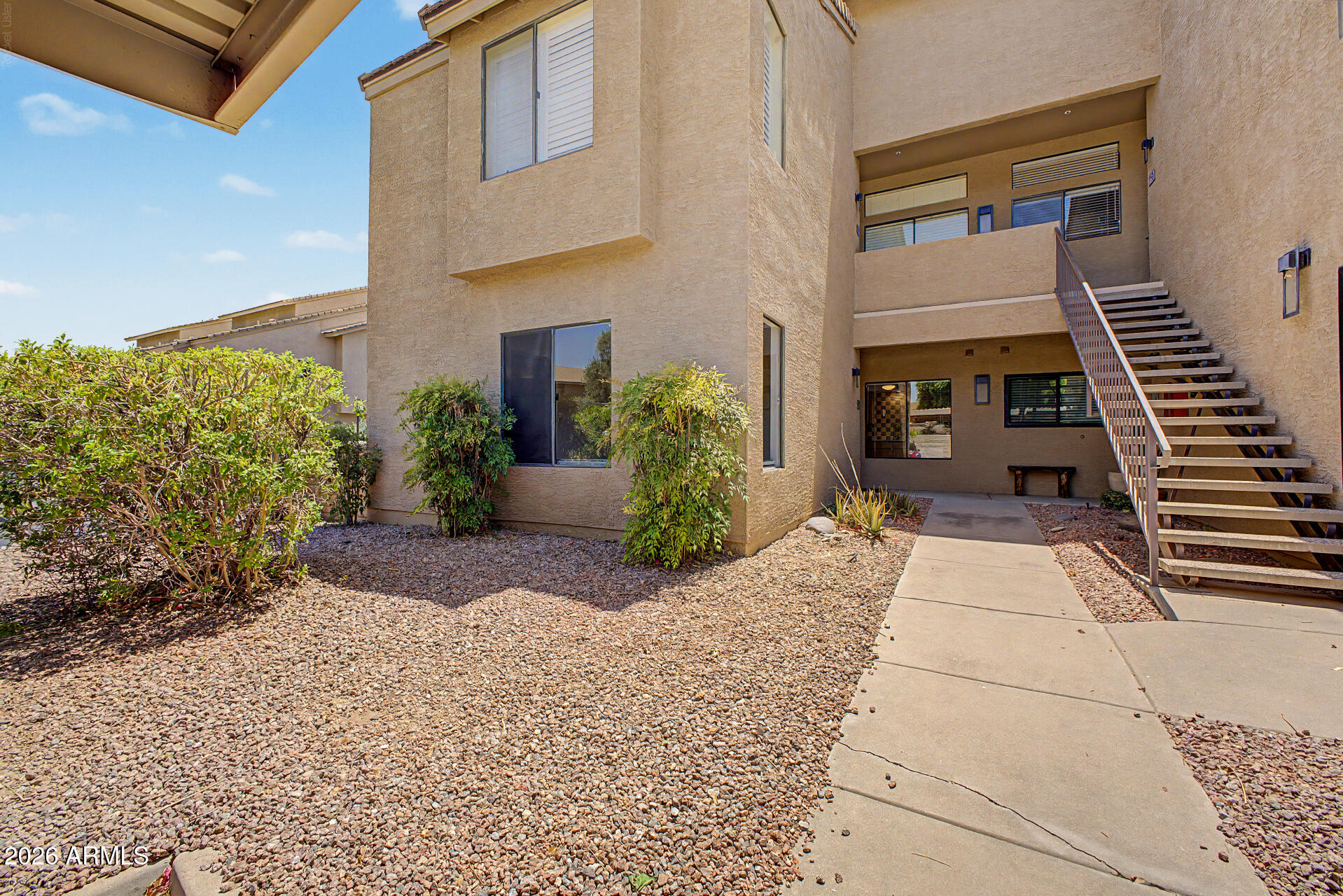 Welcome to Walden Court! Ideally located in the newest building in the community, offering a rare spacious south-facing wraparound yard backing to lush green space & just steps from Scottsdale's renowned biking and walking trails. this desirable single-level, first floor home offers a split floor plan & features generous bedrooms, spacious baths and closets, timeless wood flooring, abundant natural light, and a prime location directly across from the community pool. Recent updates include a stylish kitchen backsplash, remodeled walk-in shower, new interior paint & water heater. Security screens allow you to enjoy fresh Arizona breezes, while the indoor laundry includes newer full-size stacked washer and dryer.  This community allows Short Term Rentals. Convenient covered parking is located next to the unit, with ample guest parking nearby, making everyday living and entertaining effortless. Walking distance from Chaparral Park (dog park) and amenities