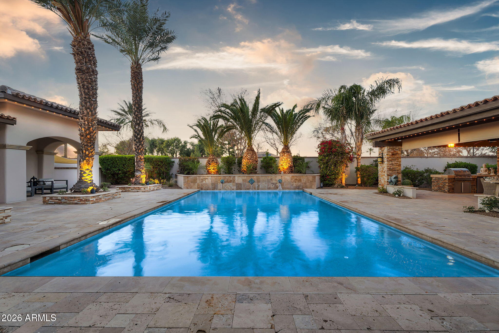 Discover this exceptional luxury residence in the gated Island at Fulton Ranch, one of Chandler's most sought-after lake communities. Situated in the heart of Fulton Ranch, this 6,492sf estate offers 6 bedrooms, 6.5 baths, and dual guest houses ideal for multigenerational living, extended guests, or private work-from-home suites. Thoughtfully designed for elevated living and seamless entertaining, the home features generous gathering spaces, soaring ceilings, and a fluid indoor-outdoor connection with ample outdoor covered square footage. The gourmet chef's kitchen showcases granite slab countertops, upgraded cabinetry, high-end appliances, and multiple ovens, while the formal living room is anchored by a Cantera-style fireplace complemented by additional fireplaces in the primary... ...bath, front courtyard, and rear yard. The primary wing offers a spa-style retreat with his-and-her vanities, marble counters, soaking tub, walk-in shower, and ample closet space with a 400sf addition off the master bedroom ideal for a professional grade studio, executive suite or private media room. Well appointed secondary bedrooms including a full bedroom and ensuite bath downstairs and dual guest houses with private ensuites and walk-in closets enhance flexibility and privacy for family or long-term stays. Outside, the resort-style backyard offers exceptional privacy and year-round enjoyment with a sparkling pool, in-ground spa, built-in BBQ, covered lounge spaces, and a spacious grassy lawn all set on an approximately 0.65-acre lot. Located within minutes of top-rated schools, upscale shopping, dining, and major East Valley employment and entertainment corridors, Fulton Ranch delivers a serene lakeside lifestyle without compromising convenience. Don't miss this rare opportunity to own in the exclusive gated enclave of Chandler's premier Fulton Ranch neighborhood!