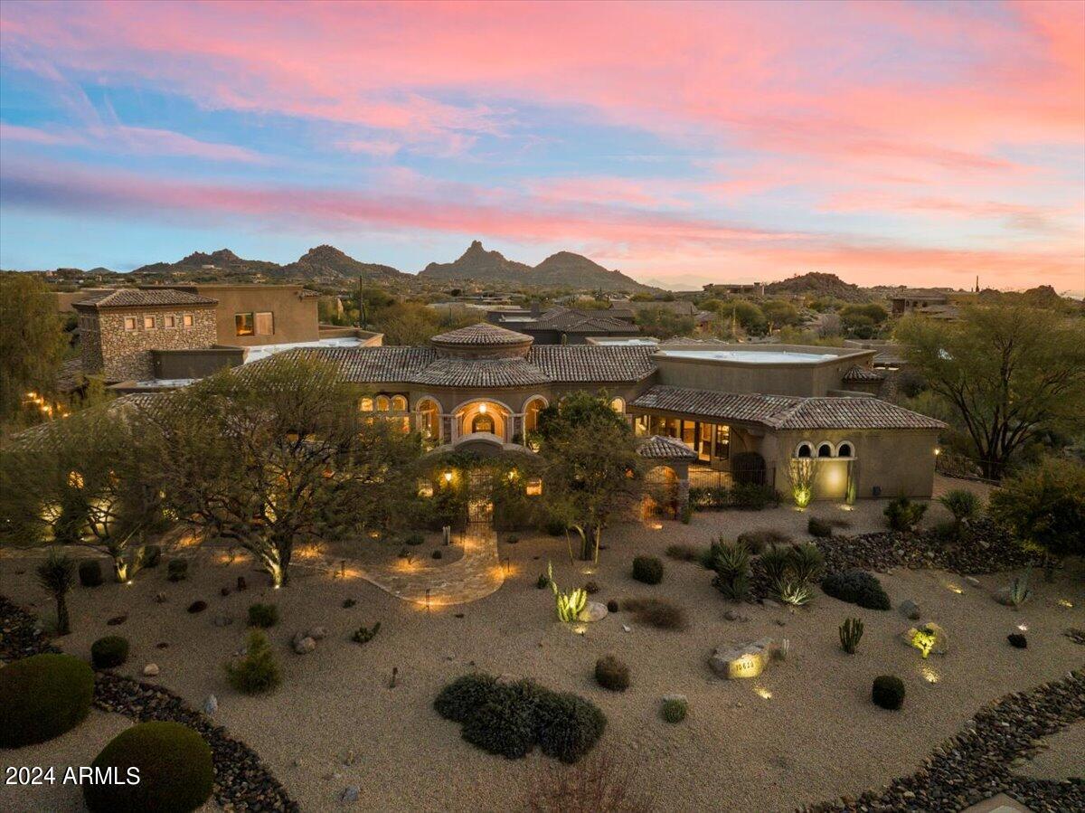 Welcome to your dream oasis in the heart of the luxurious gated community of Talus at Troon North. This stunning Italian-inspired Custom Home is a masterpiece of architectural elegance & timeless design. Nestled on an expansive ~1-acre corner lot, this home enjoys the utmost privacy within a serene cul-de-sac setting. As you approach the residence you are greeted by a grand gated entry courtyard adorned w/ two majestic fountains & lush landscaping, setting the tone for the opulence that awaits inside. With a spacious 7,443 SF of living space, this four-bedroom + HUGE upstairs BONUS ROOM, 7-bath estate offers an impressive array of features & amenities. Main level of home boasts a functional & well-thought-out floor plan. Three generous bedrooms PLUS 420SF Casita and Office...CLICK ''MORE' Four bedrooms on main level plus a stunning ensuite office w/ closet, private patio and calming water feature, all ensure ample space for family and guests. The upstairs area is dedicated to entertainment, featuring a media/game room with an exterior balcony that provides breathtaking views. This upstairs compound has bath, deck, closet & kitchenette. Upstairs BONUS ROOM easily becomes BEDROOM 5. For those seeking additional privacy, an ensuite  guest casita with a kitchenette, closet and private entrance can be found off the charming front courtyard. This home is a paradise for those who love to entertain. The kitchen seamlessly connects to the family room, complete with a wet bar and convenient access to the wine cellar, which is large enough to accommodate a tasting table. The kitchen itself is a chef's dream, featuring top-of-the-line appliances, including a Viking gas cooktop, two Wolf wall ovens, two Asko dishwashers, three sinks, and dual Sub Zero fridge/freezers. The master suite is a sanctuary of luxury, occupying its own private wing of the home. It includes a cozy sitting room with a fireplace, a sumptuous bathroom highlighted by a sunken jetted tub framed with Cantera stone columns and an inviting fireplace. Additionally, there is a safe room and even a hookup for a washer/dryer in one of the three walk-in closets, providing ultimate convenience. Every inch of this residence exudes elegance and sophistication. It is loaded with first-class amenities, including fresh interior paint and new carpet, a domed entry ceiling, an exotic pool and spa surrounded by travertine pavers (recently refinished), a three-car garage with an extra detached bay for a total of four car garages, and a total of five fireplaces throughout the home for added warmth and charm. Cantera stone accents adorn both the interior and exterior, while polished travertine flooring and electronic shades add to the overall sense of luxury. This home is simply impressive and offers a lifestyle of grandeur, elegance, and sophistication. Don't miss the opportunity to make this exquisite Italian-inspired residence your own, and experience the epitome of luxury living in the exclusive Talus at Troon North community.