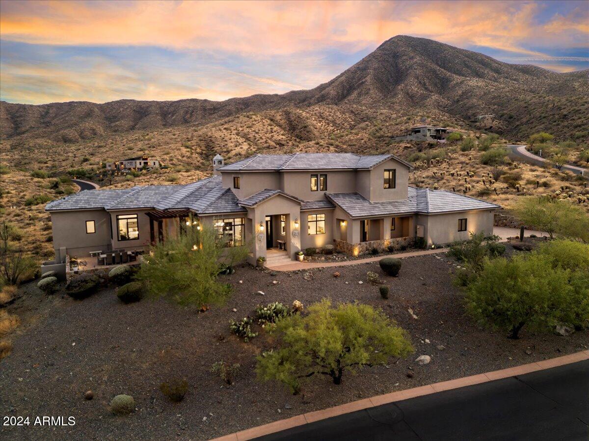 BACK ON THE MARKET, buyer could not perform. Perched high in the McDowell Mountains, this stunning transitional soft contemporary estate offers breathtaking 360-degree views of the mountains and city, with expansive panoramas visible from every room, window, and patio. Situated in the prestigious, guard-gated Eagle's Nest community of Fountain Hills, this 5 bedroom, 5.5 bathroom home, including an office, a detached casita and bonus room, epitomizes luxury, privacy, and serenity. Designed with an open and split floor plan, the home features soaring 12-foot ceilings, rare veined travertine flooring, premium wood flooring, and four perfectly positioned patios for seamless indoor-outdoor living. Meticulously maintained, this home showcases custom high end finishes throughout, exemplifying impeccable pride of ownership. The chef's kitchen is a culinary masterpiece complete with an oversized island, granite countertops, farmhouse sink, soft-close cabinetry, and a butler's pantry. It boasts state-of-the-art appliances, including a Bosch induction cooktop with pot filler, Bosch dishwasher, Thermador dual wall ovens, warming drawer, Thermador custom refrigerator and freezer, and a Gaggenau built-in coffee and cappuccino machine. The bright and spacious great room offers a formal dining space, breakfast nook, gas fireplace, and a standalone wet bar with a beverage fridge, wine cooler, full dishwasher, and seating for ten. The luxurious primary suite features a hidden bookshelf that leads to a private den or exercise room as well as a luxurious bathroom with dual vanities, a walk-through shower, a free standing jetted soaking tub, heated floors, and a large walk-in closet. Upstairs, you'll find a private guest suite with its own bath and walk-in closet, along with two additional guest rooms that share a Jack and Jill bathroom, both with walk-in closets. The detached casita comes complete with a full kitchen, butcher block countertops, stainless steel appliances, a bathroom with a jacuzzi tub, and a walk-in closet. The backyard is an entertainer's oasis, boasting spectacular mountain views and a heated Pebble Tec lap pool with an automatic cover, a private gated spa with bistro lights, a travertine pool deck, and an outdoor kitchen featuring a built-in BBQ, bar area, sink, and cooling misters for added comfort. A covered patio with fully automated sunscreens ensures year-round outdoor enjoyment. Eagle's Nest, a private enclave of 250 homes, offers scenic biking and walking paths, with easy access to nearby hiking trails. The winding roads take you through the natural beauty of the McDowell Mountains, providing stunning views of Four Peaks, the Superstitions, and the Goldfields.