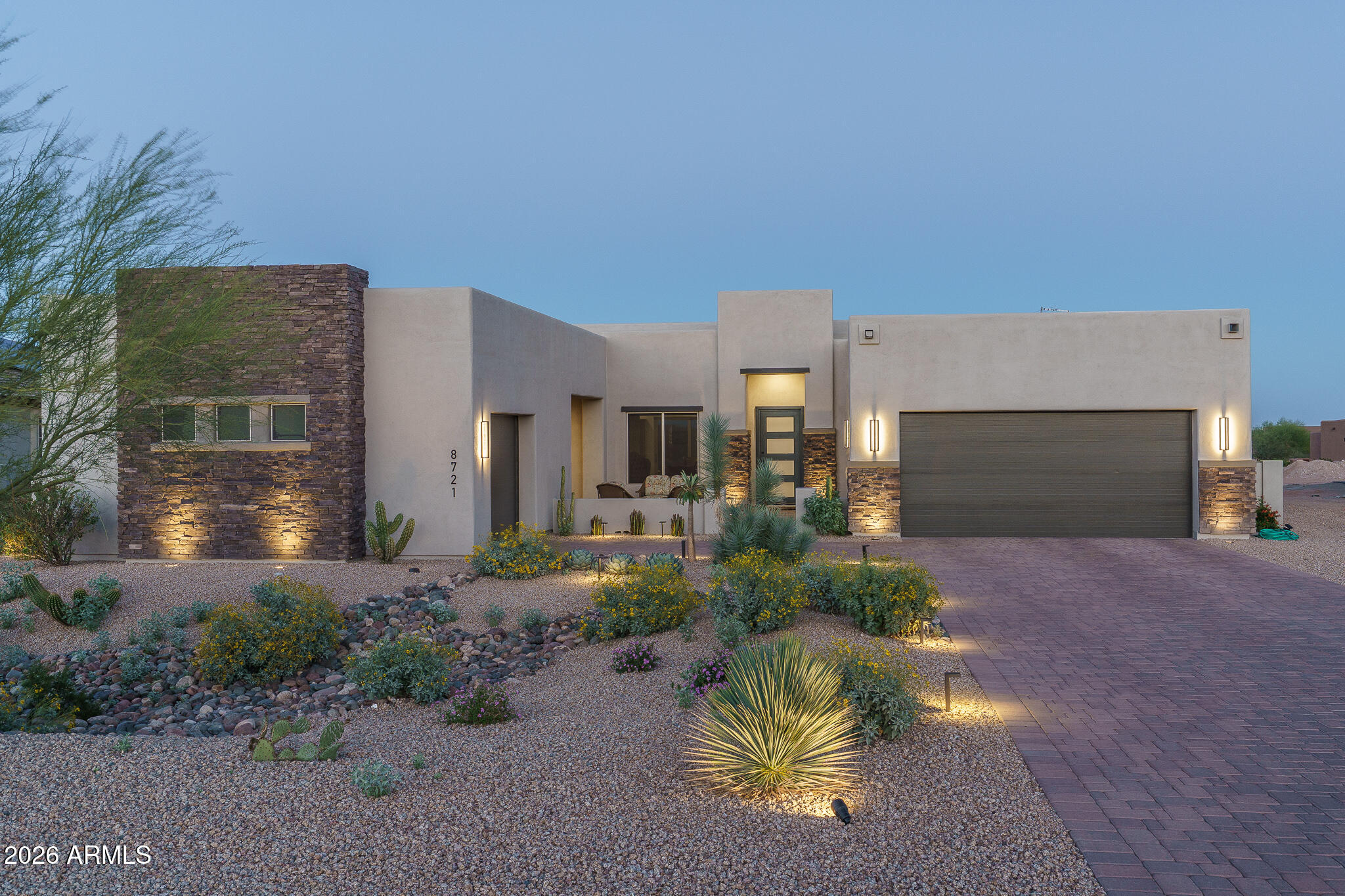 This beautifully refreshed semi-custom home in Sonoran Ridge Estates is located just minutes from the White Tank Mountain Regional Park and all that the rapidly growing West Valley has to offer. This contemporary-influenced residence offers refined sophistication across 2,820 SqFt in the enhanced Aspen floor plan, featuring 2 bedrooms plus a den (easily converted to a 3rd bedroom) and 3 bathrooms. The expansive great room boasts 12' ceilings, a striking wood-beamed ceiling, and transom windows above multi-panel sliding glass doors that seamlessly extend the living space to the covered tiled patio. The backyard offers a designated area ideal for a built-in BBQ island, perfect for enjoying the serene desert, mountain, and city light views. The chef-inspired kitchen is a true showpiece, featuring ceiling-height stacked white shaker cabinetry, quartz countertops, and a herringbone Italian marble backsplash. Premium Café stainless steel appliances include a 42" built-in refrigerator, dual-drawer dishwasher, beverage refrigerator, and a spacious walk-in pantry. The oversized island showcases contrasting gray cabinetry, farmhouse sink, Brizo fixtures, R/O system, and ample seating at the breakfast bar. The luxurious primary suite offers private patio access and a spa-like bath with dual vanities, freestanding soaking tub, oversized tiled shower, and an expansive walk-in closet. The secondary en-suite bedroom includes its own private bath and walk-in closet, providing an ideal space for guests or extended family. Additional highlights include a custom laundry room with 42" upper and lower cabinetry, built-in sink, Brizo designer faucet, and Italian marble backsplash. The oversized 2-car garage features an 18' x 8' insulated door, epoxy flooring, storage cabinets, water softener, water conditioner, and R/O system. A separate third-car split garage with matching epoxy floors offers incredible flexibility as a home gym, art studio, or workshop, and includes a service door leading to the front covered paver courtyard with beautiful mountain views.