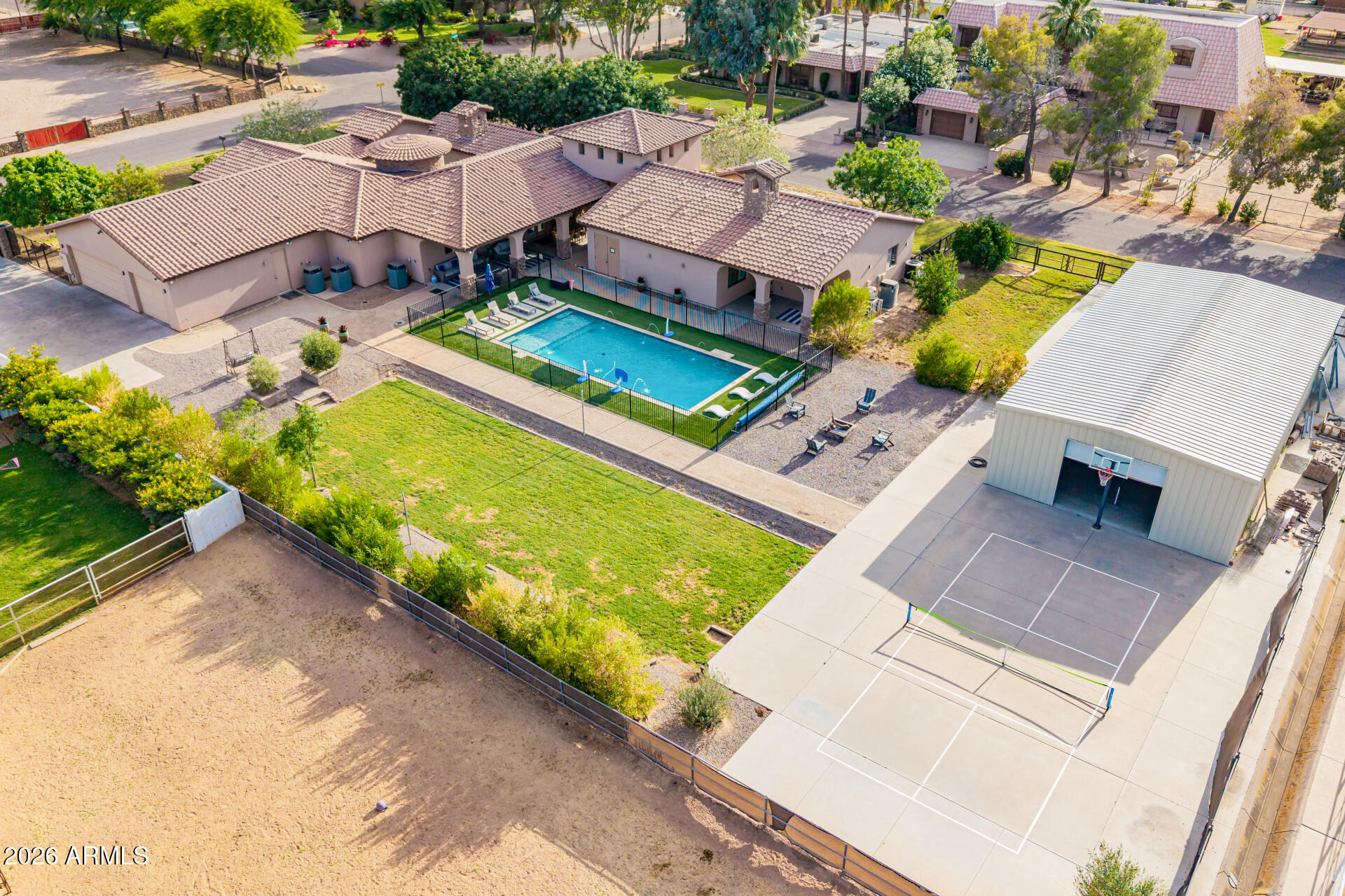 Resort-style estate on 0.82 acres in Gila Butte Estates -- no HOA. 4 beds, 4 baths total across a 3,266 SF main home + detached 1,154 SF guest house. The main residence delivers soaring ceilings, wood-look floors, plantation shutters, and a chef's kitchen with granite counters, tile backsplash, walk-in pantry, and stainless appliances. The primary suite opens to a private sitting room with outdoor access, walk-in closet, and a dual-vanity ensuite. Step outside to a sparkling 20x30 pool, expansive covered patio, and a guest house ideal for multi-generational living, a private home office, or income. Premium corner lot with stone-accent facade, front courtyard, 3-car side garage, RV gate, and insulated detached storage. Built 2010. Turnkey, move-in ready. A rare South Chandler compound. Secondary bedrooms share a Jack & Jill bath, and a separate den works as an office or reading nook. The detached guest house has its own living room and a well-appointed kitchen. Out back: extended seating areas, a hot tub, a fenced pool, a tennis court, and a detached RV garage.