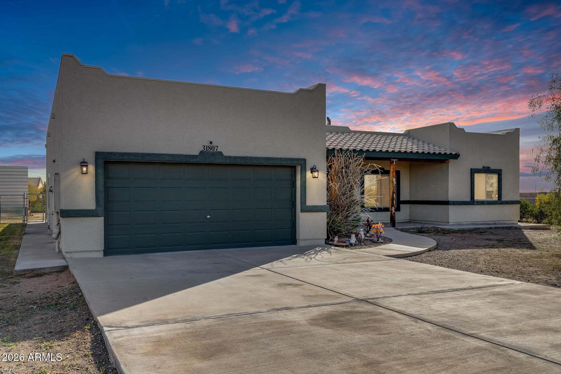 Wide-open space, desert serenity, and total freedom—no HOA! This updated 3-bed, 2-bath home sits on over an acre with breathtaking White Tank Mountain views, offering quiet living and endless possibilities. Enjoy a spacious great room, a split primary suite with walk-in closet and full bath, and a functional kitchen with pantry, ample cabinetry, and refrigerator included. Recent upgrades include a new roof (2020) and exterior paint (2022). Outside, you'll find an extended driveway, RV parking with RV cover, and a concrete pad—perfect for a shop or storage. Covered front and back porches invite you to relax and take in the desert views. Ideal for equestrian use, expansion, or custom projects, this property delivers privacy, flexibility, and room to grow.