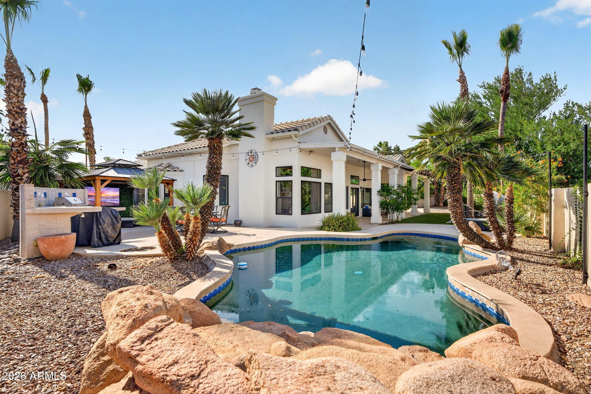 Immaculate single-level home tucked away on a premium cul-de-sac lot in the heart of Scottsdale. Offering 2,432 square feet, this thoughtfully designed residence features 3 bedrooms, 3 full bathrooms, and a dedicated office, blending comfort, functionality, and timeless style. An elegant foyer welcomes you into the open-concept living, dining, and kitchen spaces, highlighted by neutral tones, abundant natural light, and a cozy fireplace in the living room.
The spacious kitchen is designed for both everyday living and entertaining, complete with quartz countertops, a breakfast bar, cooktop island, pull-out shelving, and extensive cabinetry for storage and organization. The split primary suite provides a private retreat with dual closets, including an oversized walk-in closet with custom shelving. The ensuite bath features dual vanities, a jetted soaking tub, and a walk-in shower. Two generously sized secondary bedrooms are connected by a Jack-and-Jill bath with separate vanities for added convenience.
Step outside to a beautifully manicured backyard designed for Arizona living, featuring a sparkling pool with water feature, extended covered patio, built-in BBQ, gazebo with television, artificial turf, and ample space to relax or entertain. Additional highlights include a 3-car garage with over-height third bay, abundant storage throughout, and new windows and two newer AC for enhanced efficiency and comfort.