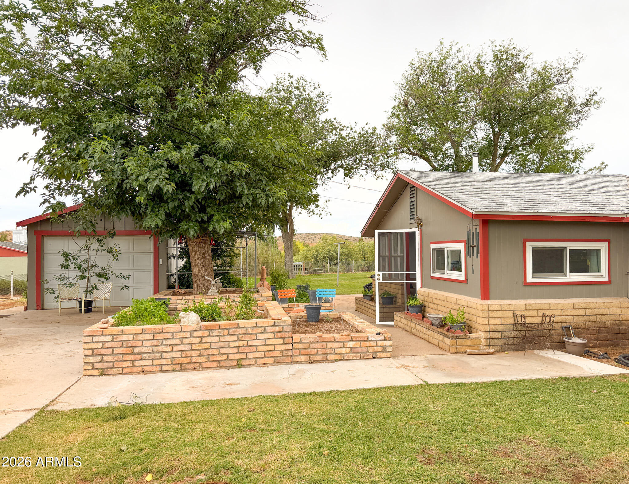 Bring your homestead dreams and enjoy 360-degree views from your sustainable farmhouse on 1.91 acres in rural Cornville, AZ. Multiple accessory buildings offer plenty of storage for your farm equipment & hobbies.  Featuring owned solar with 4 back-up batteries, TWO wells & newer 1,500-gallon septic system installed to accommodate future expansion. Build your dream home or add a guest house. This all-electric home has a cozy wood burning fireplace insert with automatic fan & includes almost 3 cords of highly seasoned firewood. Additional amenities include; water softener, kitchen sink RO, one riding lawn mowers & pull behind sprayer. Farm animals and horse property. Many updates of major systems in 2021-2022 include: HVAC, water heater, 200-amp service, flooring, & kitchen/bath remodel. Located in a secluded and hidden neighborhood with one road in/out that some describe as a "peninsula" due to Oak Creek wrapping around this neighborhood like a horseshoe. This tightknit community works together to maintain Sugarloaf Road which is a private road. On the drive in, admire the handywork of their coordinated efforts as recent maintenance has just been completed. 

The first accessory building is a 1-car detached garage approximately 12 X 18 in size with a 12 X 12 bonus room on the backside. This bonus room is the perfect "hang-out space" with TV & internet already installed. Would make a great hobby room too! The second accessory building is roughly 900 sq feet with four separate spaces; the rear farm equipment garage, the rear garden/tool room, the storage room & the open multi-purpose area. This open multi-purpose area could be used for many things including a workshop. It already has a wood stove pipe installed and houses one set of well equipment and water softener.  The third accessory building is a 10 X 12 Tuff Shed with covered front porch set on a slab. Lastly, the fourth accessory building is rumored to be almost 100 years old with original barnwood. Repurpose the barnwood or bring your chickens and use it as a chicken coop or animal pen!

Water is very important in Arizona and there are TWO wells on this property. One is dedicated to serve the house & has a water softener. The second is dedicated to serve the yard & livestock. There is a separately fenced garden area with a couple of fruit trees, among them are two varieties of peach trees. As well as pomegranate and apricot. Some trees located in other parts of the yard. The almost one acre surrounding the main house is cultivated with green grass and multiple shade trees for outdoor enjoyment and entertaining. The perimeter of the 1.91 acres is fully fenced.

Inside you will find, 3 bedrooms and 1 bathroom with a bonus room. This bonus room would make a great office or oversized mud room/laundry room. In addition, there is a secure walk-in pantry with floor to ceiling shelving with upright full size freezer included (please note - room not photographed). The kitchen was remodeled in 2022 with updated cabinets & countertops. Kitchen features dishwasher, full size refrigerator and lots of countertop space. Eat-in-kitchen nook has room for a bistro table for two. Living room features wood fireplace with blower insert and antique built-in hutch. Dining room and living room are open concept while the kitchen is in a separate room. The bathroom has a step-in shower with grab bars. Water heater and washing machine located in bathroom closet. Washer/Dryer included. 

Home built in the 1950's before permitting. In recent years, 200-amp service was installed with a permit and APS oversight.  1.91 acres cannot be subdivided due to zoning density. However, a guest house could be added. Or a new larger main house could be built, making the original farmhouse into a guest house. Guest house size allowances are based on ratio, meaning that the larger the main house is, then the larger the guest house can be. Buyer to verify with Yavapai County Planning & Zoning all information regarding permitting and available uses for this parcel. Also, NO restrictions on short-term rental possibility!