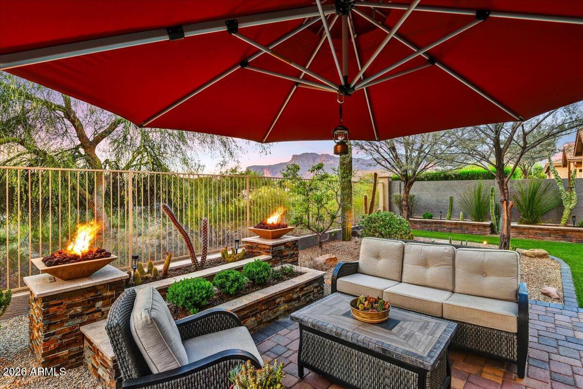 Tucked along a private natural arroyo with front-row views of iconic Superstition Mountain, this exceptional single-level home is the one that raises the bar.

A thoughtfully designed split floor plan balances comfortable everyday living with spaces built for entertaining and the low-maintenance desert yard makes lock-and-leave living effortless. Inside, soaring ceilings, generous windows, solar tubes, and rich wood plank flooring create a light, airy atmosphere throughout. Every inch of flooring is either hardwood plank or tile -easy to love, easier to maintain. The fourth bedroom doubles as an office with custom bookshelves that conceal a space-saving queen Murphy bed -form and function at their best.

The kitchen and bathrooms have been tastefully updated with quality finishes that feel intentional, not trendy. Linger over dinner with Flatiron views framed by your dining room window -- a nightly reminder of exactly where you live. In the living room, a custom live-edge juniper mantle flanked by matching shelves and a stacked stone surround creates an entertainment niche so striking, the 85" TV almost plays second fiddle.

Then step outside and stay a while.
The covered patio opens to a beautifully appointed outdoor living space designed for both intimate evenings and effortless entertaining. A custom water feature, a gas fire pit, and two gas-fired fire bowls cast a warm glow across the paver stone patio as Superstition Mountain shifts through its evening palette of amber, rose, and violet. Whether you're hosting a crowd or quietly watching the last light fade behind Flatiron, this backyard delivers exactly the kind of moment people move to the desert for.

The garage alone will sell this home.
This isn't your average three-car garage -- it's a fully insulated, air-conditioned, purpose-built space outfitted with custom cabinetry, a stainless steel sink, refrigerator, sleek epoxy floors, and a custom driveway treatment. Currently operating as a pottery studio, it transitions effortlessly into a home gym, workshop, or the ultimate hobby retreat. Whatever you envision, the infrastructure is already there.
Solar panels and whole-home added insulation mean you'll actually enjoy living in the Valley of the Sun -- with energy bills to prove it.

Superstition Foothills is Gold Canyon's best-kept secret.
Low HOA fees unlock year-round access to a heated community pool and spa just one block away, a pet-friendly park, and 52 trailheads woven throughout the neighborhood with direct links to hiking and walking trails. Gold Canyon's four golf courses -- two private, two public -- are minutes away. The community is actively pursuing a dark sky designation, and the starry nights are already extraordinary. Iconic trails in Tonto National Forest, afternoon escapes to Canyon Lake, and easy access to US-60 put the best of the region within reach.
When you need the city: Phoenix Sky Harbor is 40 minutes out, Mesa Gateway Airport 20, San Tan Village Mall 25, and medical, retail, and dining are just 10 minutes away.