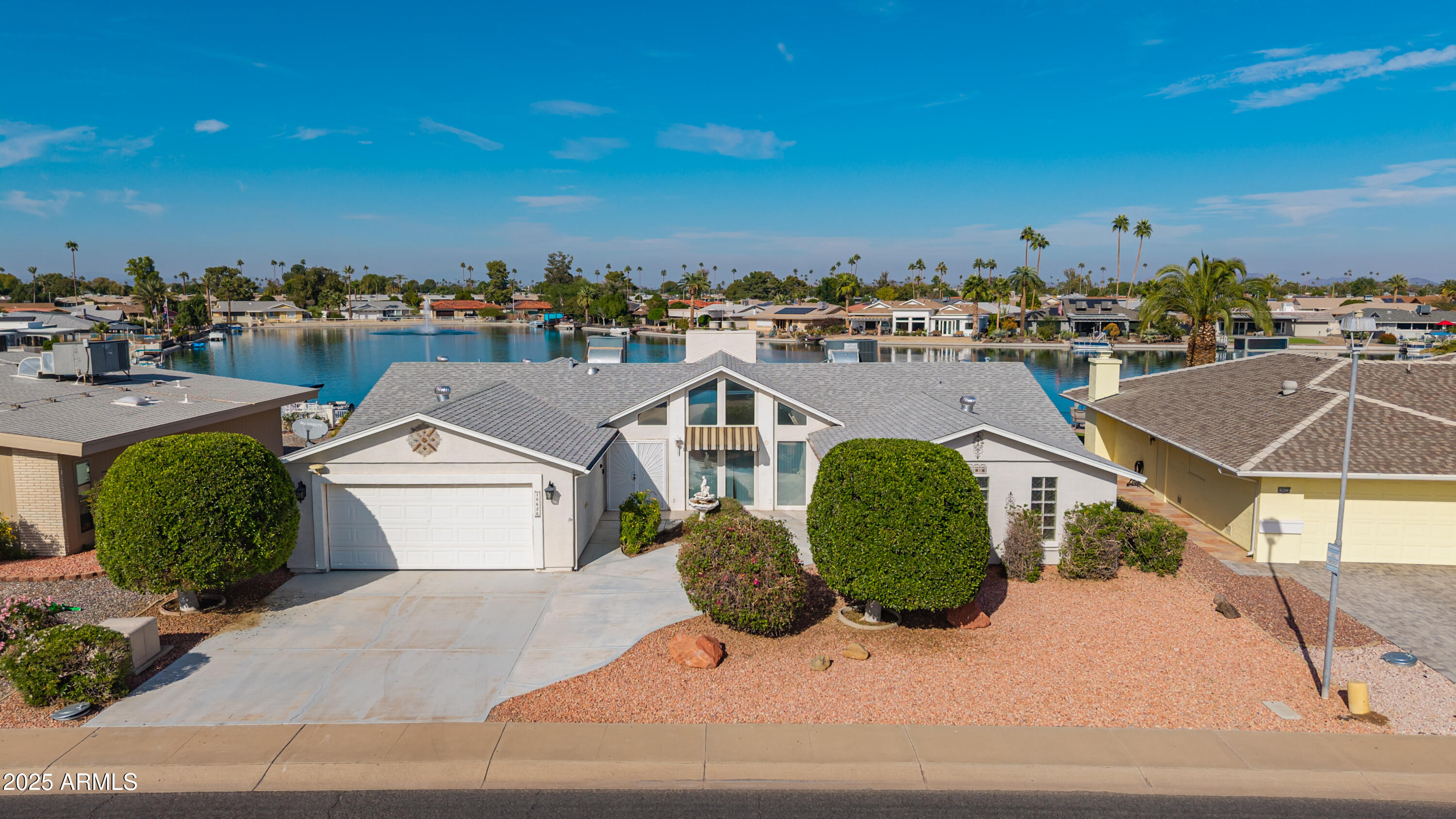 Enjoy stunning lake views from several rooms in this 3BR/3BA home on Viewpoint Lake in Sun City's sought-after age-restricted community. Step into a spacious living room with vaulted ceilings and a cozy fireplace, then stroll into the family room—complete with a second fireplace and panoramic water views. The kitchen offers abundant counter space and stainless appliances, with a nearby laundry room and separate den. The primary suite features a bay window overlooking the lake and an en suite bath. Bedroom 2 includes access to extra storage and a golf cart garage, while Bedroom 3 is conveniently located near a full bath. Relax year-round on the covered patio and soak in the serene lakeside setting. Eighty-one homes surround the 33 acre lake, which boasts many activities!