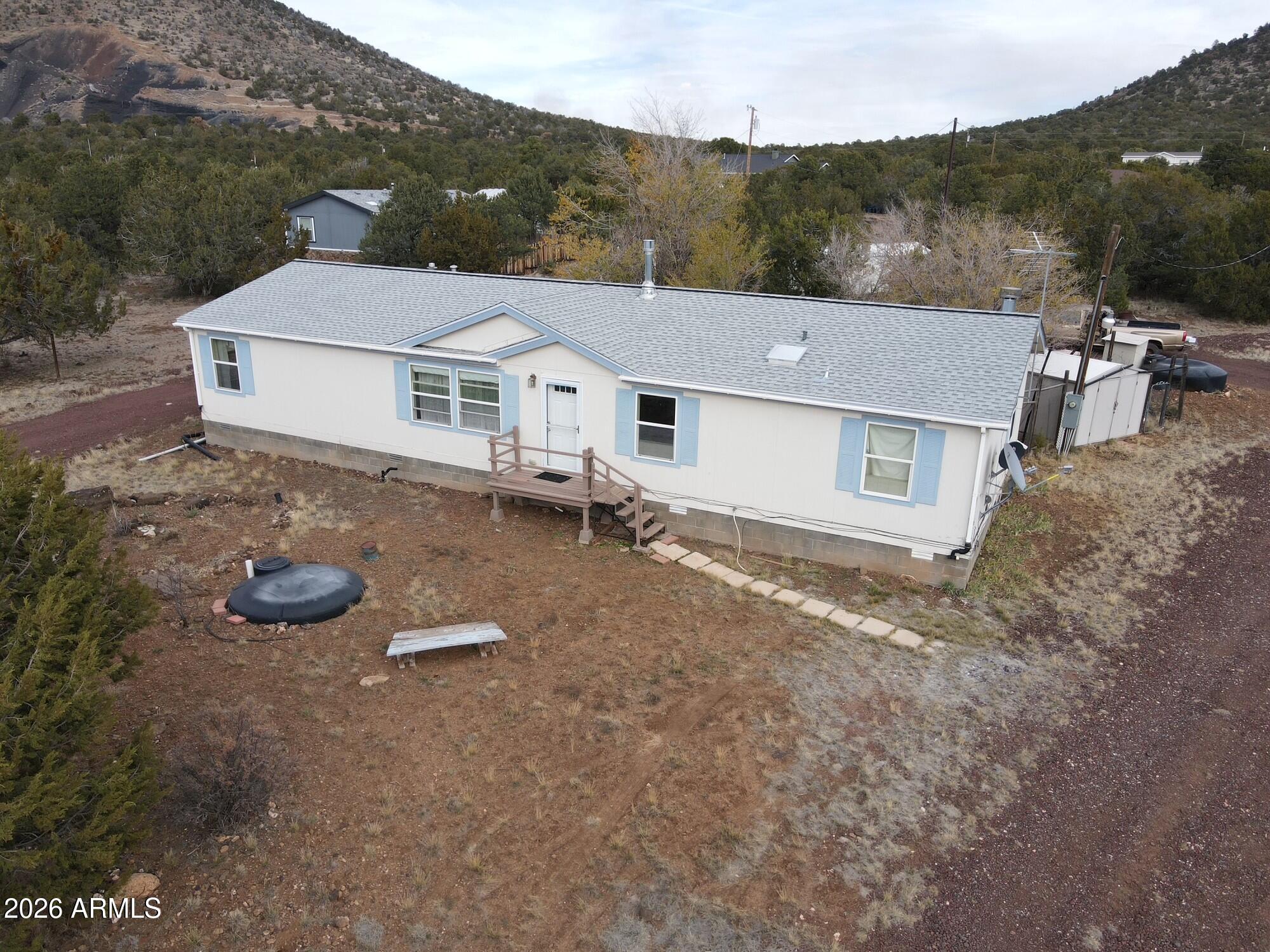 This 1792-sq ft manufactured home sits on an acre of land just north of Williams, AZ.  It is a 3-bed, 2-bath home with STEM WALL. The home features: forced air propane, AC heating and cooling, large family room, wood fireplace in den, propane gas stove in the living room, large kitchen, large primary bedroom and bathroom with garden tub. There are several storage sheds, a covered screened in porch, fenced dog run, garden area and more.