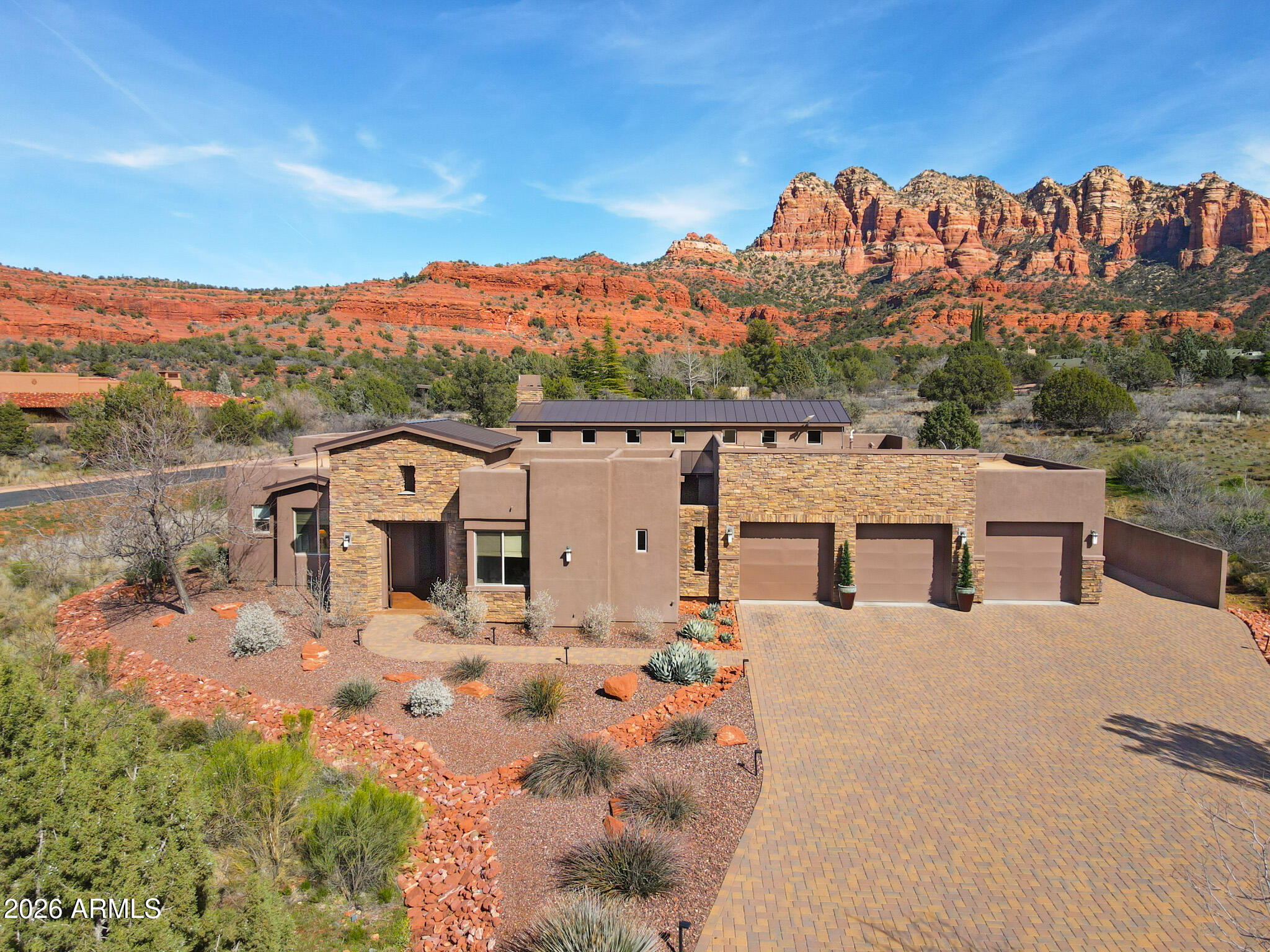 Nestled in one of Sedona's most desirable residential enclaves, this Southwest contemporary home offers an exceptional blend of privacy, architectural elegance, and breathtaking red-rock views of Cathedral Rock and Seven Warriors. This luxury 4-bedroom, 3,133-square-foot courtyard residence is situated on over an acre of desert landscape. Designed to seamlessly connect indoor and outdoor living, the home welcomes you through striking estate doors that open into a stunning courtyard design. When opened, the home transforms into a breezy, open-air retreat perfect for enjoying sunsets. There is a private guest casita and 3-car garage with a gym. This property is located in one of the most coveted destinations in the American Southwest, known as Sedona. The 4th BR is multi-functional. Enter through an exclusive gated entrance to a peaceful setting with expansive red rock views. Surrounded by natural beauty and close to scenic hiking trails, this property offers the perfect blend of privacy and outdoor adventure.

Nestled in one of Sedona's most desirable residential enclaves, this Southwest contemporary home offers an exceptional blend of privacy, architectural elegance, and breathtaking red-rock views of Cathedral Rock and Seven Warriors. This luxury 4-bedroom, 3,133-square-foot courtyard residence is situated on over an acre of desert landscape. The fourth bedroom, is actually a multi-use room, such as extra sleeping, media, study, crafts, etc. Designed to seamlessly connect indoor and outdoor living, the home welcomes you through striking estate doors that open into a stunning courtyard design that begins with a charming casita and an entertainment-friendly courtyard featuring a fire pit and tranquil water feature. An impressive engineered front door opens to a spacious living area anchored by a dramatic floor-to-ceiling stone fireplace, creating a warm and striking focal point for the home.

The gourmet kitchen features built-in Wolf appliances, including a Sub-Zero refrigerator, designed for both everyday living and entertaining. Decorative lighting highlights the space, illuminating the large island above and the cabinetry below. Just off the kitchen, a generous wet bar provides the perfect setting for hosting and gathering.

The home features an Arizona room perfect for intimate seating, enjoying the evening glow on the surrounding red rocks, and/or stargazing from the Arizona room or from the back patio.

The rear patio captures fabulous views and is designed for exceptional outdoor living, featuring an expanded seating area with an adjacent dining space, a built-in BBQ, and a relaxing spa--perfect for unwinding at the end of the day.

A spacious 3-car garage affords parking and storage. An additional room, currently being used for exercise, is another multi-use area.