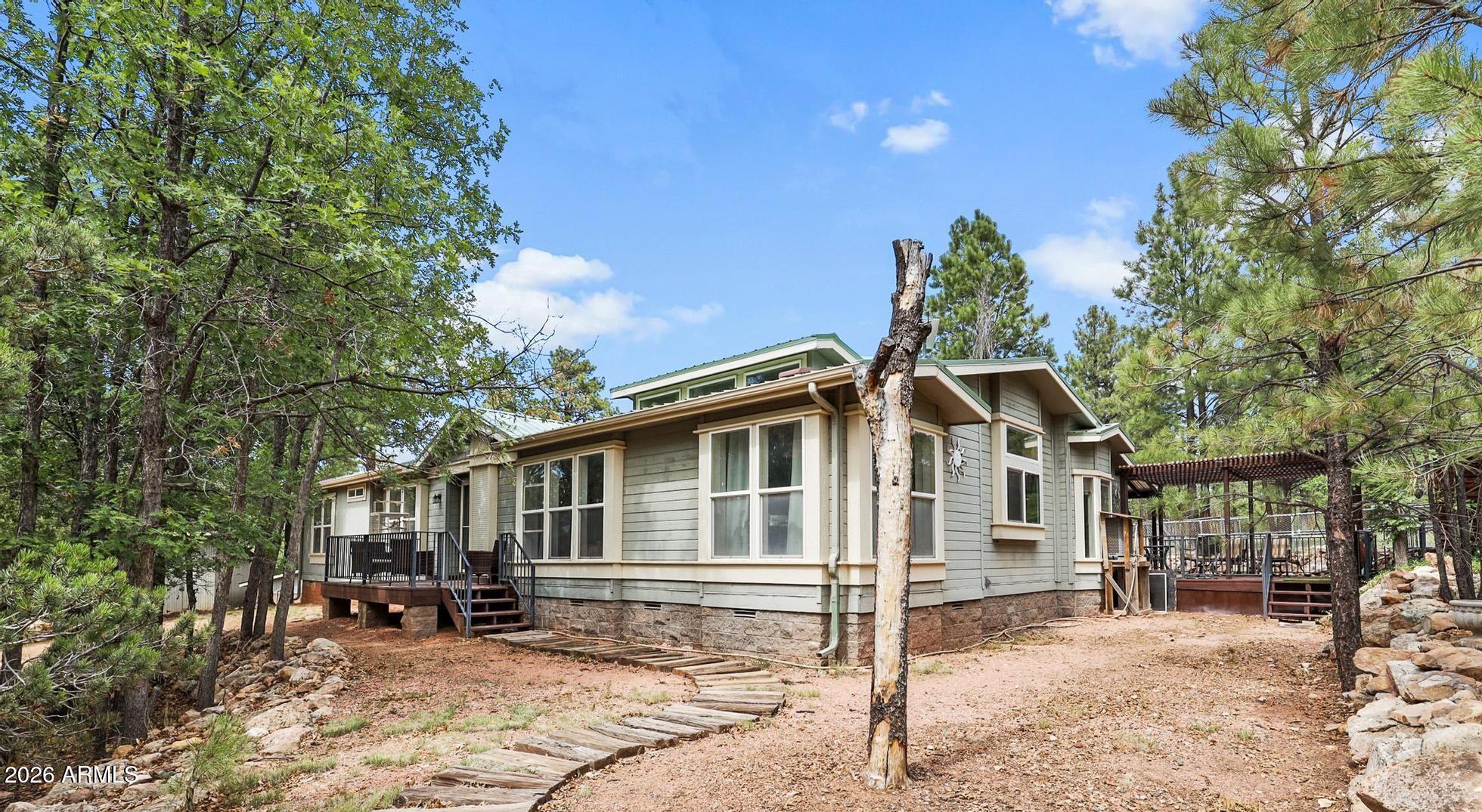 ASKING PRICE REDUCED by $$46,000!! Endless possibilities to enjoy on this super spacious acre property, beginning with the home, located on a dead-end road 500 ft from the National Forest with many trails. Kitchen boasts a large walk-in Pantry, Breakfast Bar plus a center Island.  New owners will enjoy many ideas utilizing the many rooms in this triple-wide home. Presently there are 4 bedrooms, 2 ½ bathrooms, 2 dining areas & 2 great rooms.  These large rooms allow for a multitude of uses and enjoyment. The main bedroom, with French doors that open to an inviting deck, has an adjacent bathroom with jetted spa tub.  So many amenities for comfort and pleasure. Owners try to keep the yard groomed for all 4 seasons & added a gathering fire pit area. The large Workshop used to be a mare motel.. could be changed into any use the new owner will choose. Metal roof was new in 2015. Roads are maintained by Coconino County in winter weather, and circular driveway with RV gate helps make parking easily accessible. RV pad has hook-ups , the yard has a dog run, and the Well house is in excellent condition since owner made it worry-free.  Come up and enjoy this fresh mountain neighborhood - great people too!