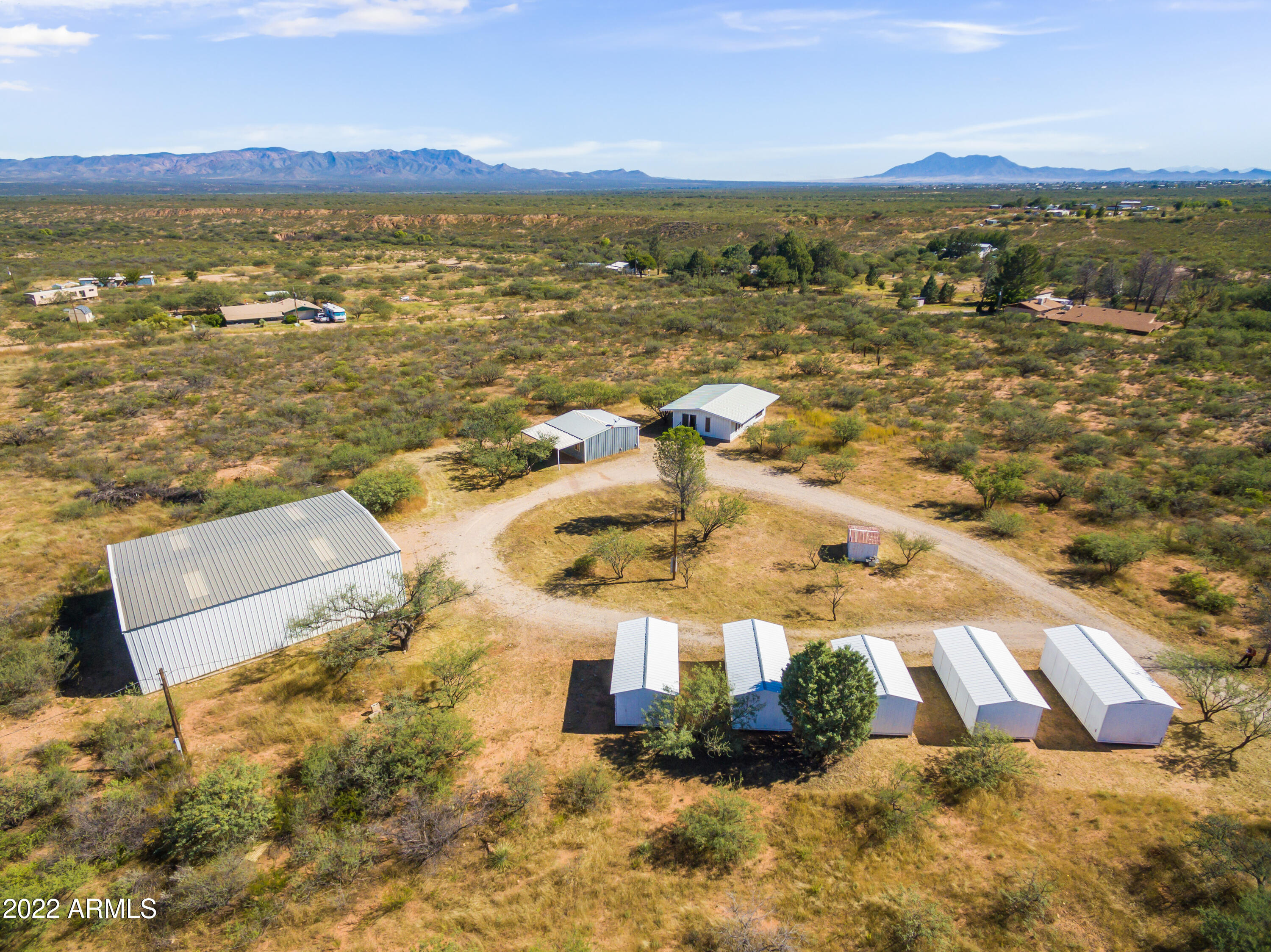 Calling all hobbyists, auto enthusiasts, tinkerers, craftspeople of all sorts! Don't miss this chance to have your very own 2000 sf steel workshop and five (Count them! Five!) durable storage sheds, on nine acres of land with mountain views! Simplify your life by living in the tiny home with one bathroom and kitchenette, solidly refurbished with metal box-tubing siding and metal roof. Separate garage includes RV hookup and flush-out connection.  Private well with two pressure tanks!  Workshop includes 4-post car lift and separate electric meter; wired for 220... use your welders and air compressors! Endless possibilities just waiting for you to make it your own!