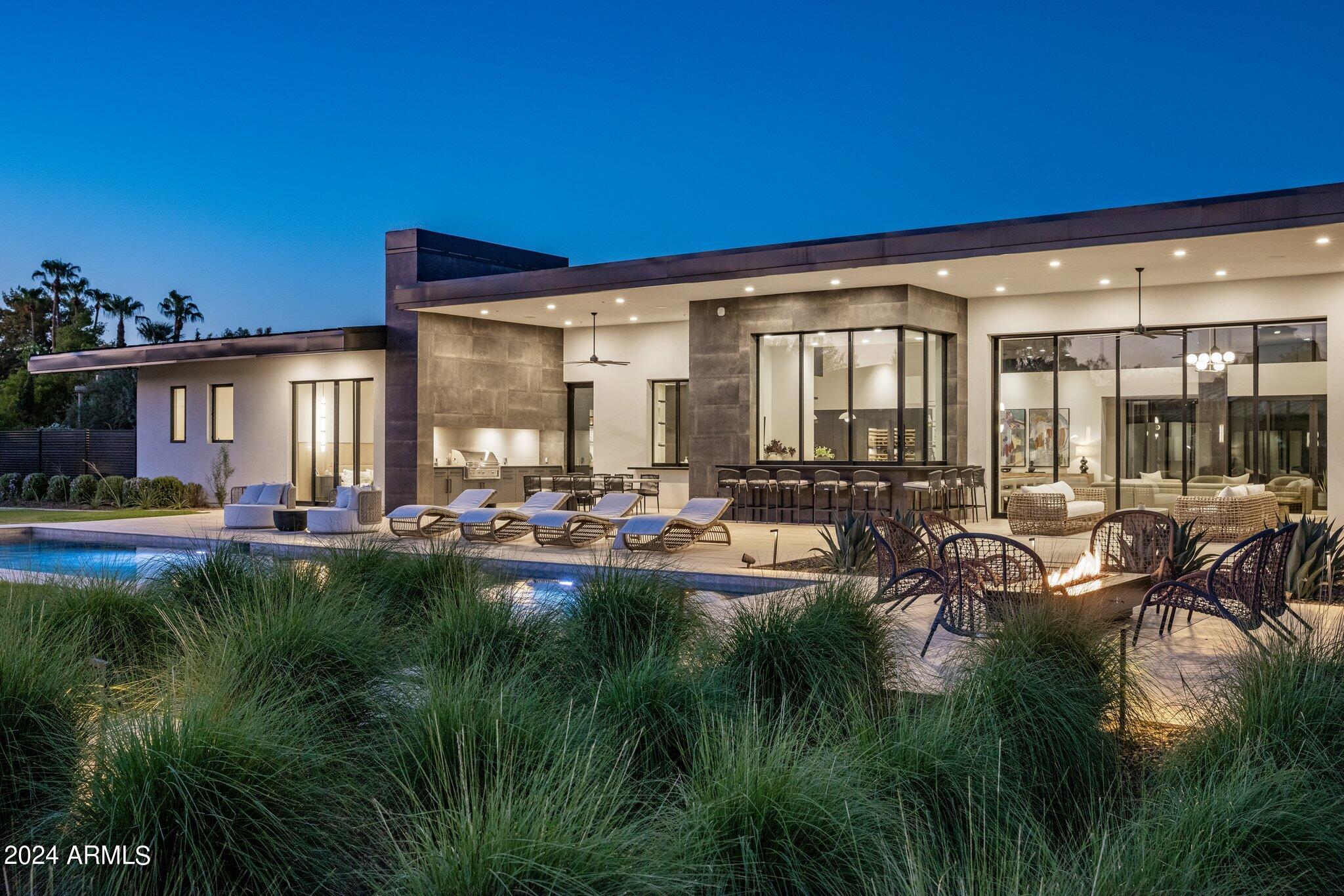 Experience unparalleled luxury in this completely gated private, 5876 square ft 2023 modern home, perfectly nestled on a flag lot near the Ritz. This architectural masterpiece offers soaring ceilings and retractable floor-to-ceiling custom glass walls, seamlessly blending indoor and outdoor living. The expansive great room flows into a chef's kitchen, fully equipped with Eggersman cabinetry, Sub-Zero, and Wolf appliances, creating the perfect space for entertaining. The estate features 5 spacious bedrooms and 5.5 bathrooms, ensuring comfort and privacy for all. A large guest house with its own kitchen, living room, and separate bedroom offers an ideal retreat for visitors.Step outside to find a large grassy play area complete with a putting green, perfect for enjoying Arizona's sunny days