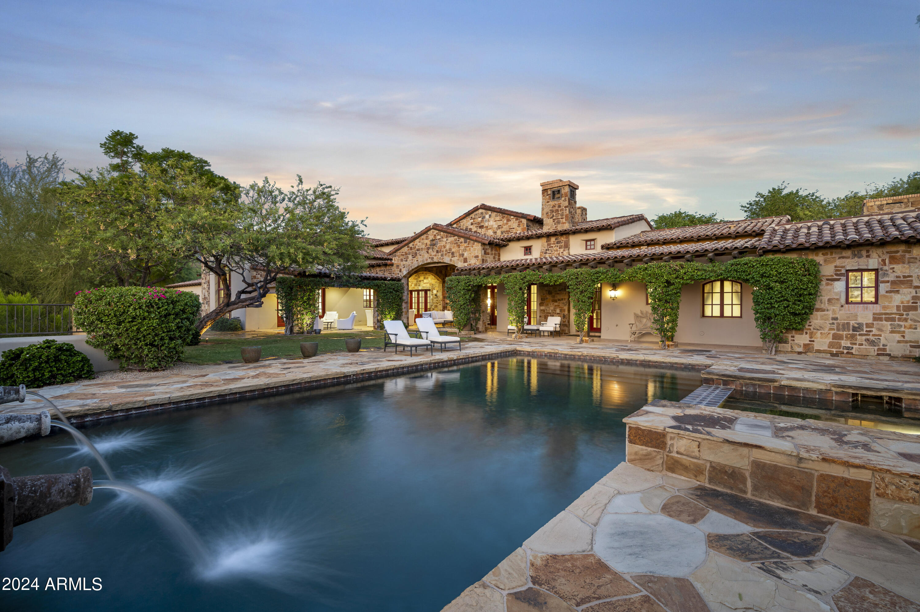 This exquisite home, beautifully updated and perfectly situated on a prime lot backing to the Reata Wash, is located in the highly sought-after Arcadia Silverleaf neighborhood. It offers breathtaking mountain and city light views while providing the ultimate in privacy and the best of Arizona living. 
This stunning residence features luxurious modern Spanish details and unmatched, expansive outdoor spaces. With 5 ensuite bedrooms, 5.5 bathrooms, & a bonus room, the home boasts an open, light, and bright floor plan adorned with limestone and hardwood flooring, Cantera stone fireplaces, and a gourmet kitchen equipped with quartz and marble waterfall counters, custom cabinetry, eglomise mirrored glass backsplashes, Sub-Zero and Wolf appliances, two Bosch dishwashers, a butler pantry w with a Sub-Zero wine fridge, and two refrigerator drawers. The spacious laundry room includes ample cabinetry and an ice maker.

The private primary retreat offers a sitting room with a cozy fireplace, a coffee/beverage center, his and her closets, his and her water closets, and a grand two-sided entry steam shower. Wine enthusiasts will appreciate the dedicated wine tasting room with a temperature-controlled wine wall that holds 864 bottles, complemented by an additional wine cellar for 212 bottles. The backyard is an entertainer's paradise, perfect for enjoying spectacular Arizona sunsets with a heated pool and spa, serene water features, electric sun shades, an outdoor kitchen, and a wood-burning fireplace.

The immaculate oversized three-car garage features epoxy flooring and ample storage cabinets. Recent upgrades to the property include all new HVAC units, updated Pentair pool equipment, an updated lighting system, and two new tankless hot water heaters to ensure modern comfort and convenience. For a comprehensive list of features and upgrades, please refer to the documents tab. This home is truly exceptional and is sure to appeal to the most discerning buyers, with its ideal proximity to shopping, dining, and the 101 freeway. The best of location, luxury, and lifestyle.